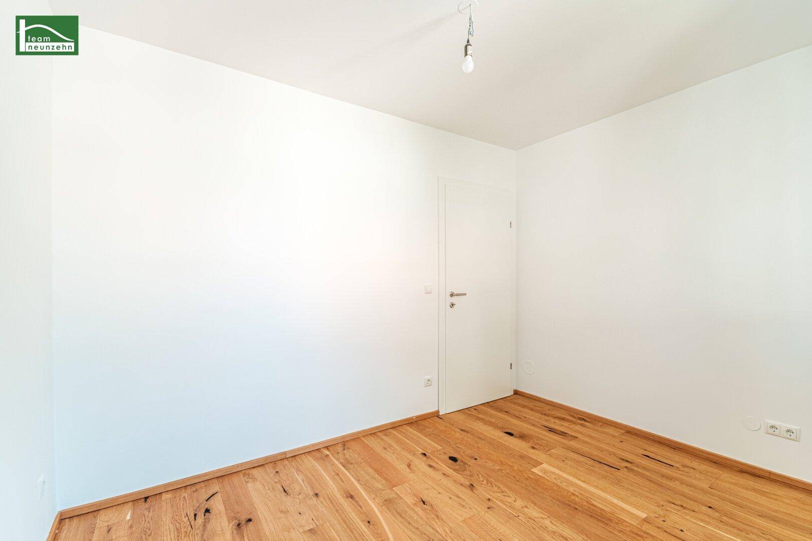 Leerer Raum mit Holzboden und weißer Tür, bietet Potenzial für verschiedene Nutzungen.
