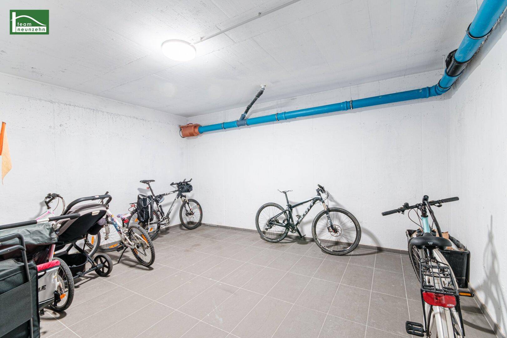 Gemeinschaftlicher Fahrradraum im Keller mit mehreren Fahrrädern und Kinderwagen abgestellt.