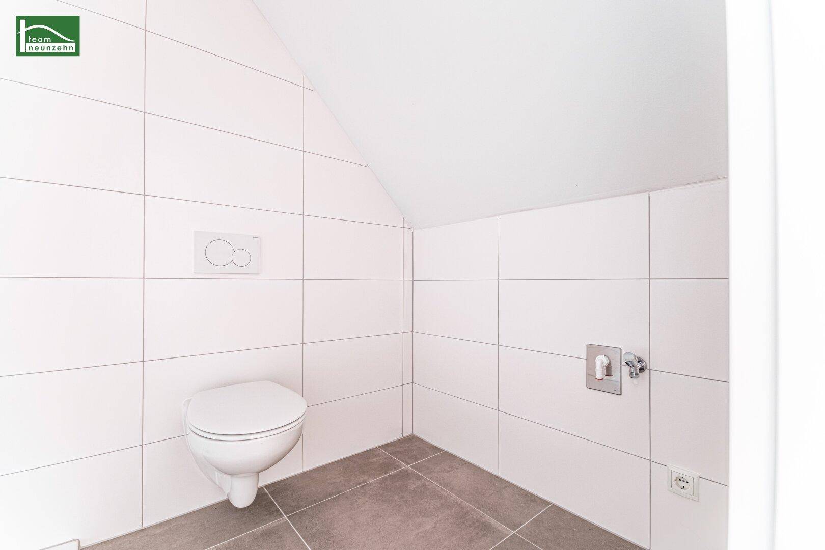 Modernes WC mit weißen Fliesen und wandhängender Toilette in einem hellen Raum.