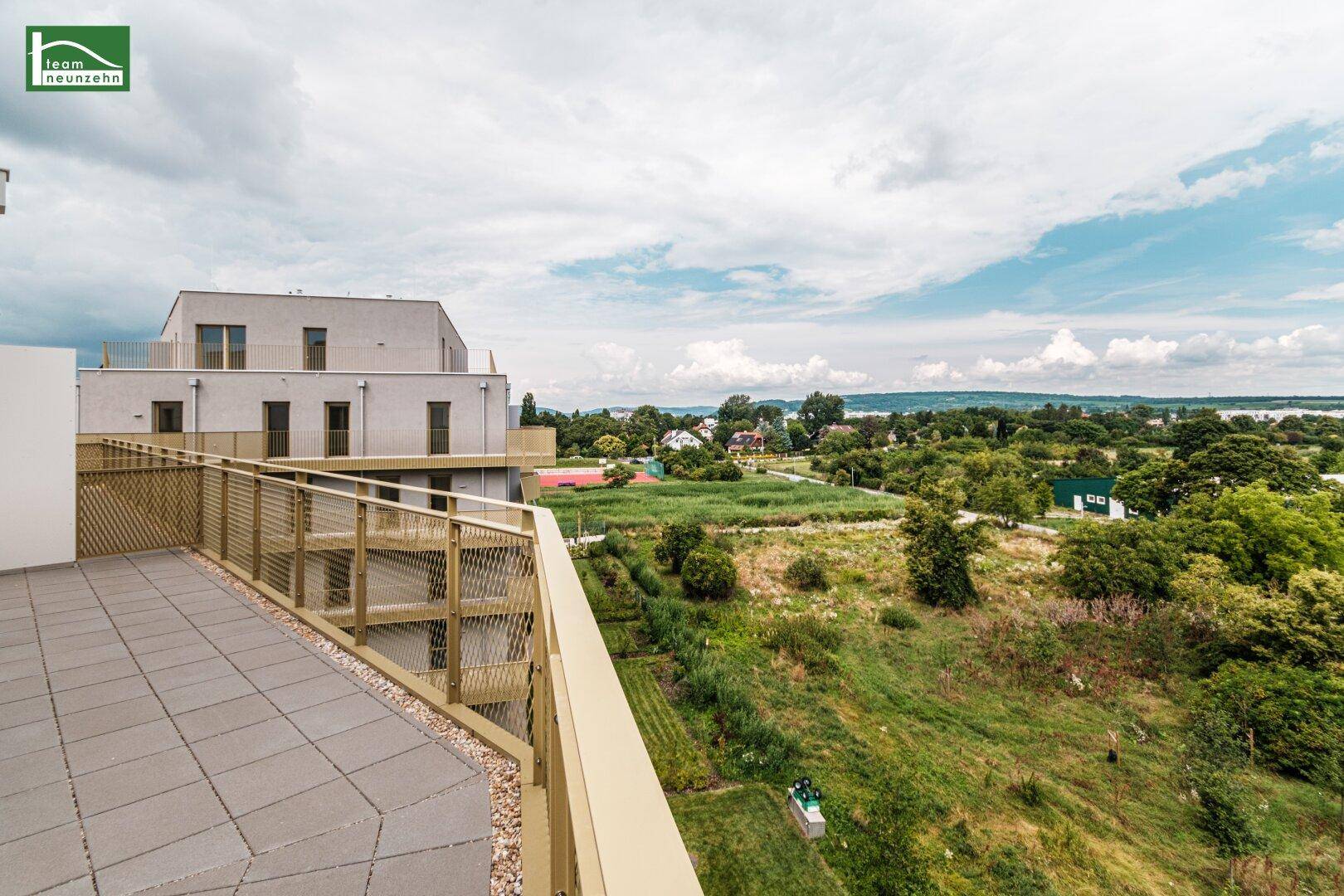 Große Terrasse mit Fliesenboden und weitem Blick über die grüne Landschaft und einen See.