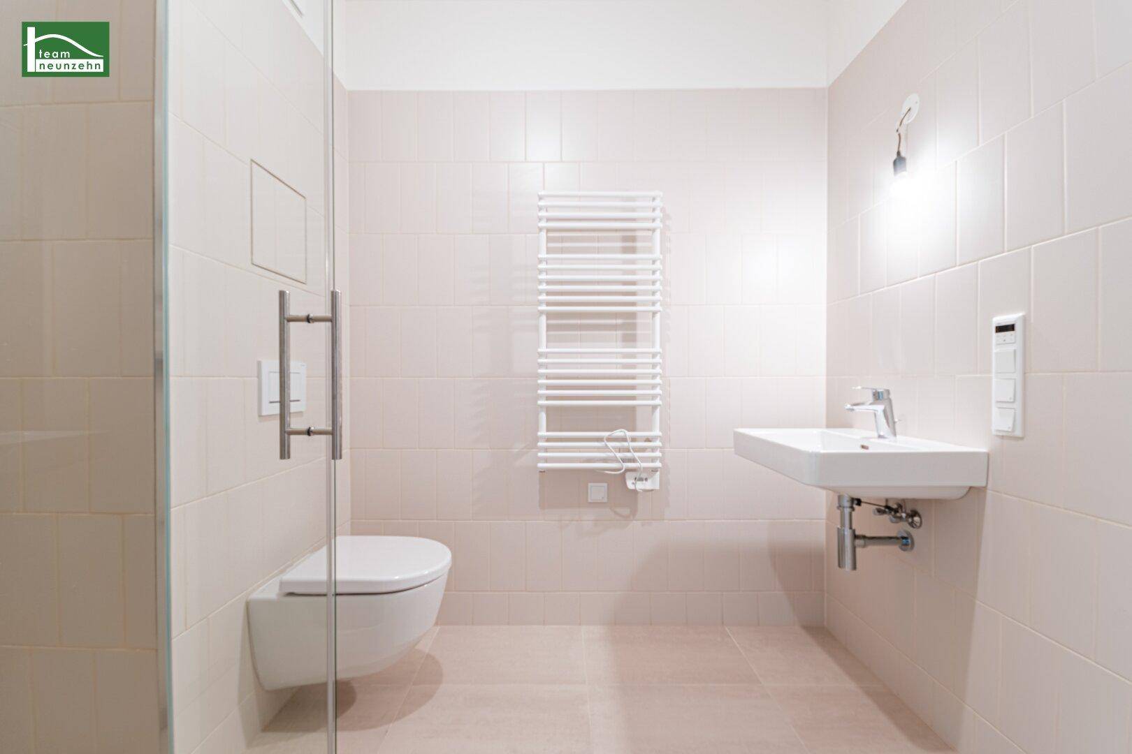 Helles Badezimmer mit wandhängendem WC, modernem Waschbecken und beheiztem Handtuchhalter.