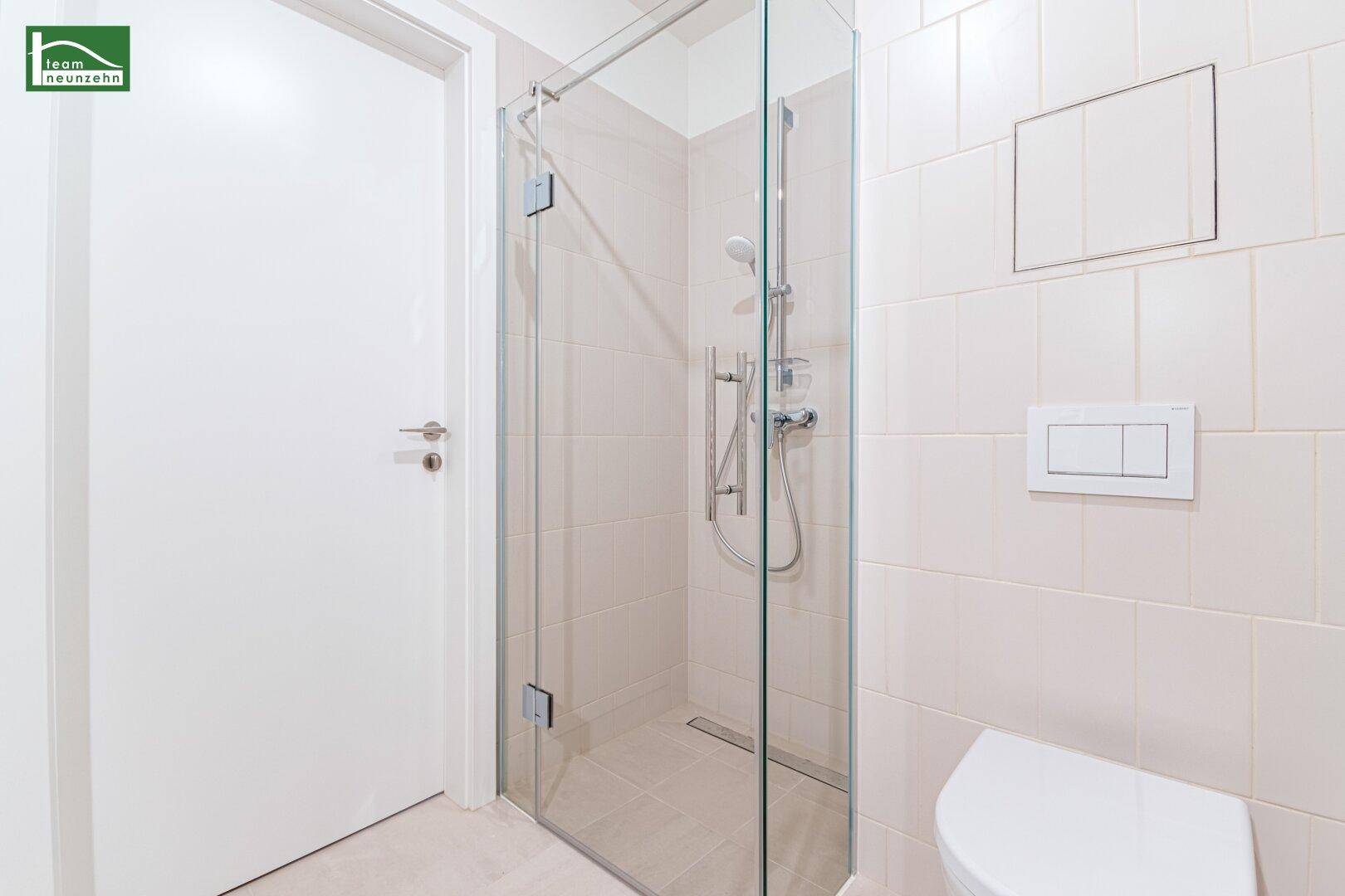 Modernes Badezimmer mit begehbarer Dusche und hellen Fliesen, funktional und zeitgemäß gestaltet.