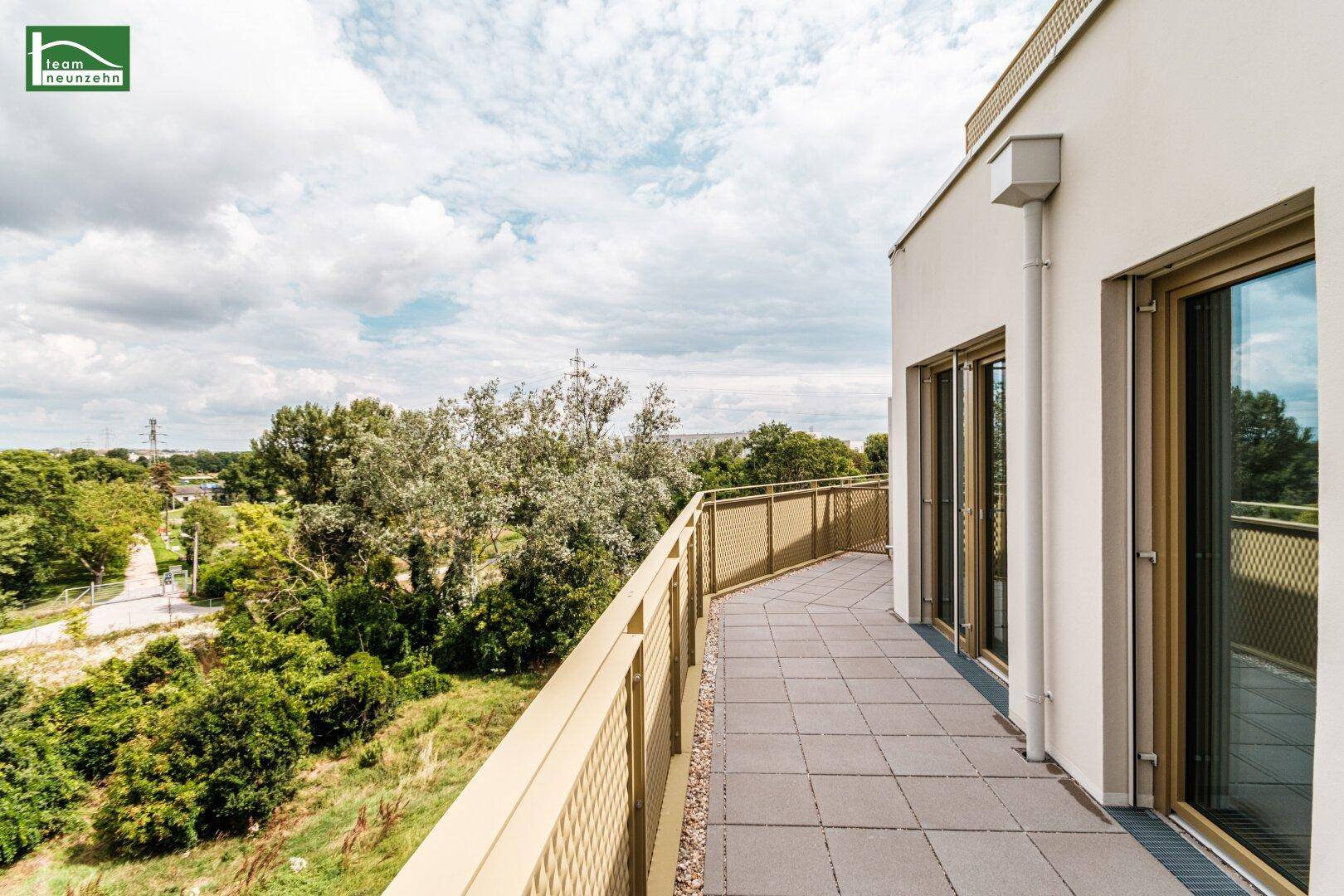 Langer Balkon mit Fliesenboden und moderner Metallbrüstung, bietet einen weiten Blick ins Grüne.