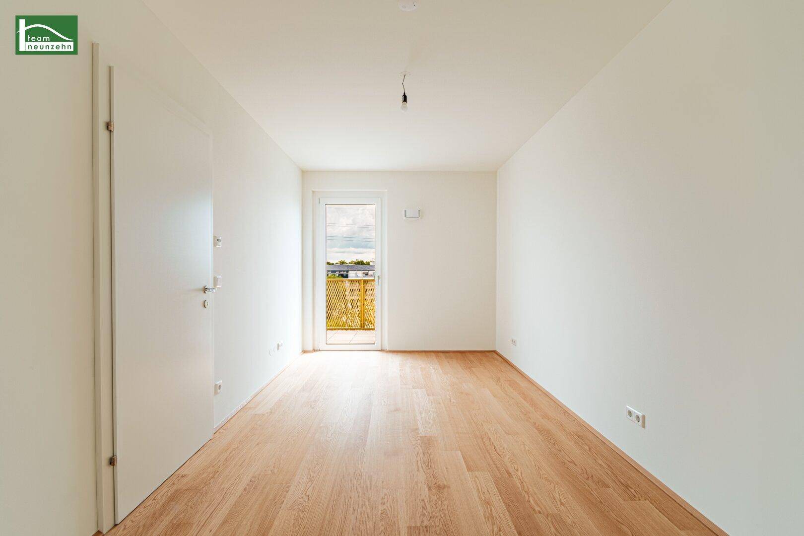 Helles Zimmer mit Holzparkettboden und direktem Zugang zu einem Balkon, ideal als Schlaf- oder Arbeitszimmer.