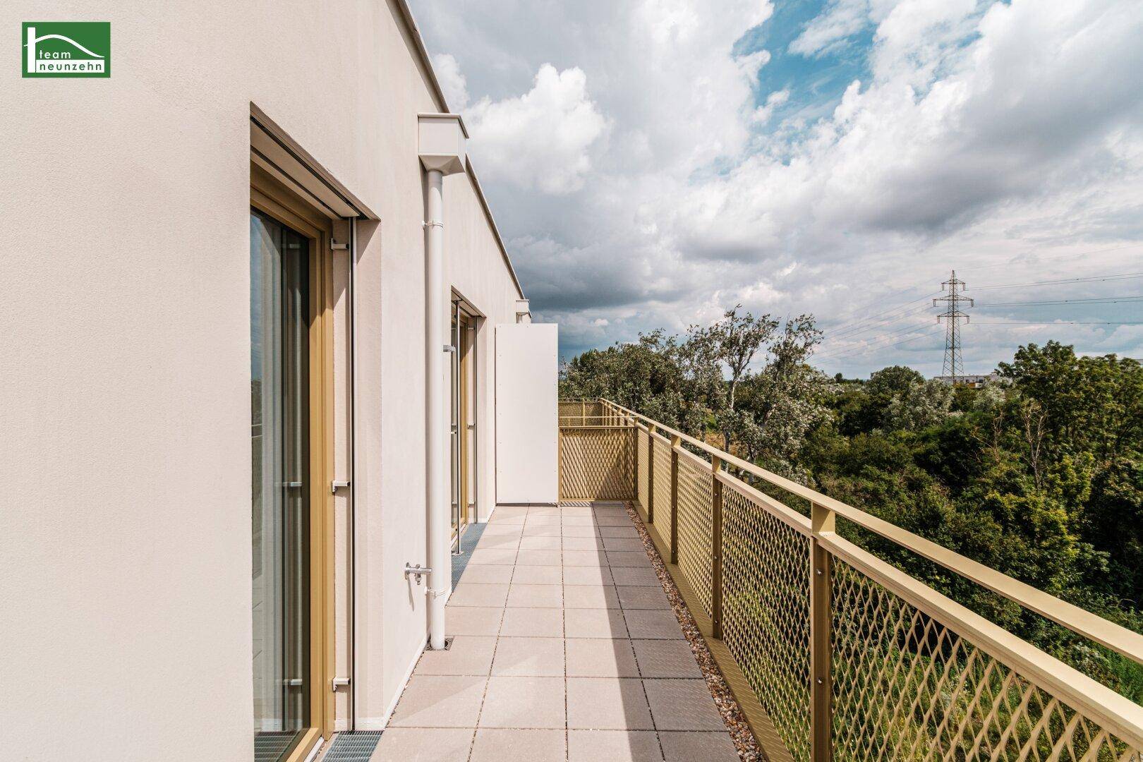 Langer Balkon mit modernen Metallgeländern und Blick ins Grüne.