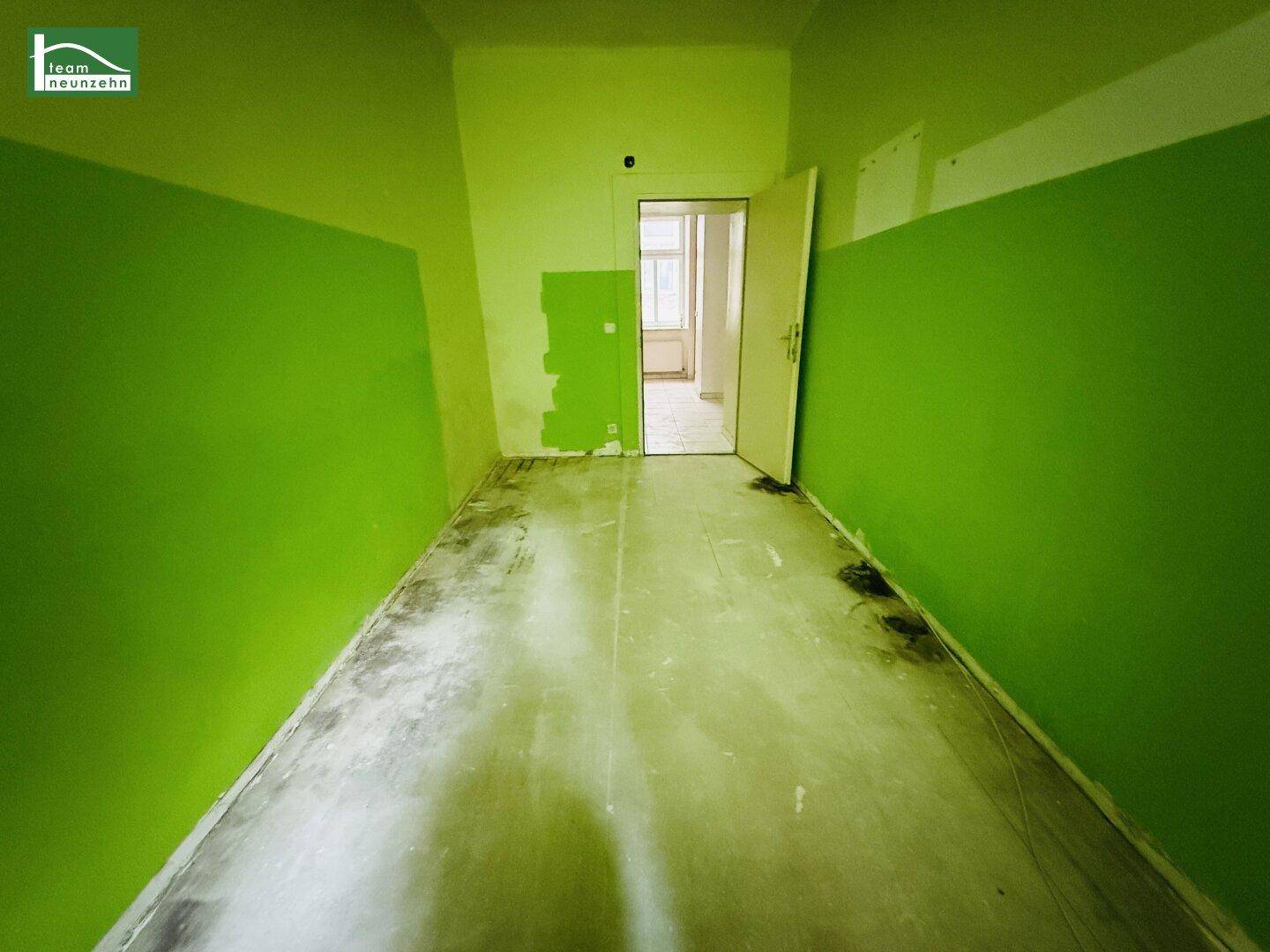 Leerer Raum mit grünen Wänden und offener Tür zu einem weiteren Zimmer.