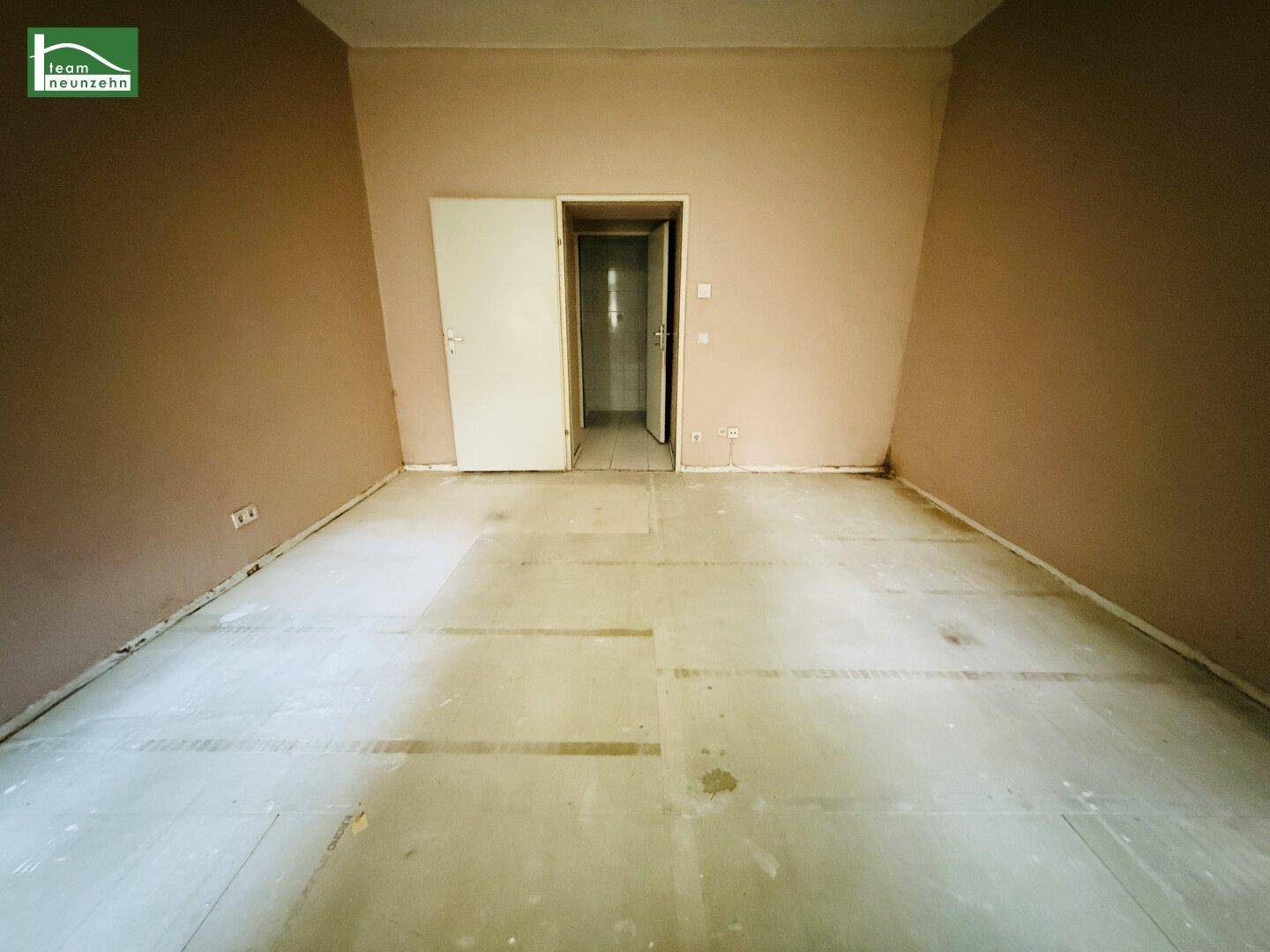 Leerer Raum mit braunen Wänden und offener Tür zu einem angrenzenden Badezimmer.