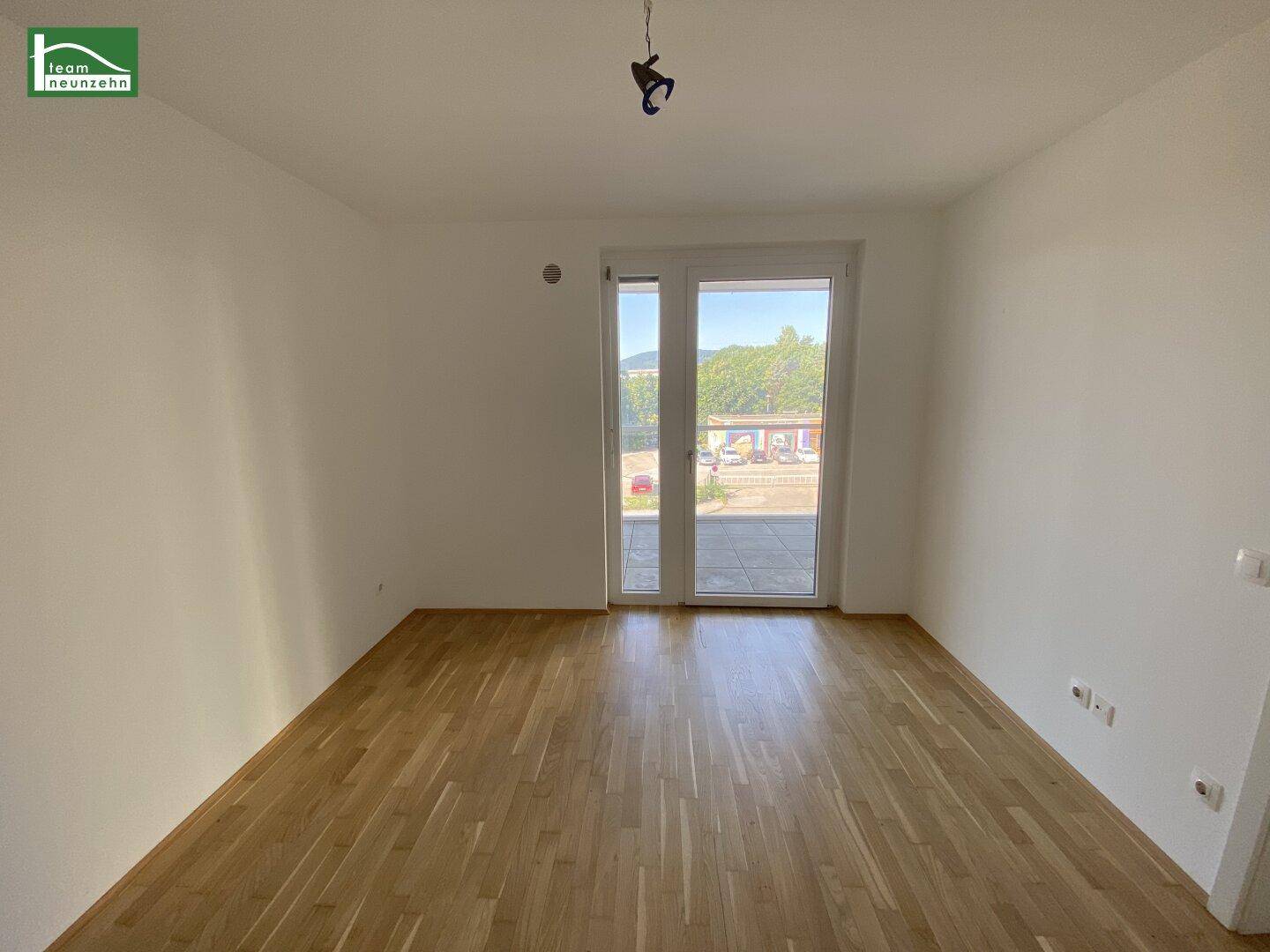 Leeres Zimmer mit Parkettboden und großer Balkontür, ideal als Schlaf- oder Arbeitszimmer.