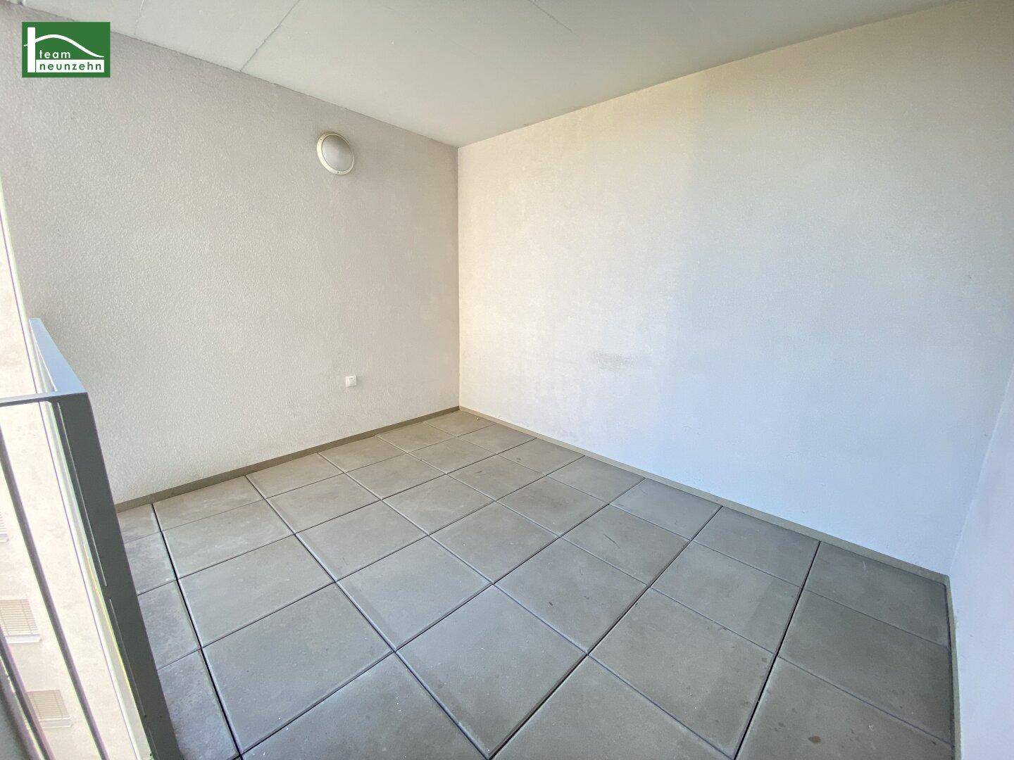 Heller Balkon mit Fliesenboden und schlichten weißen Wänden, ideal für Entspannung im Freien.
