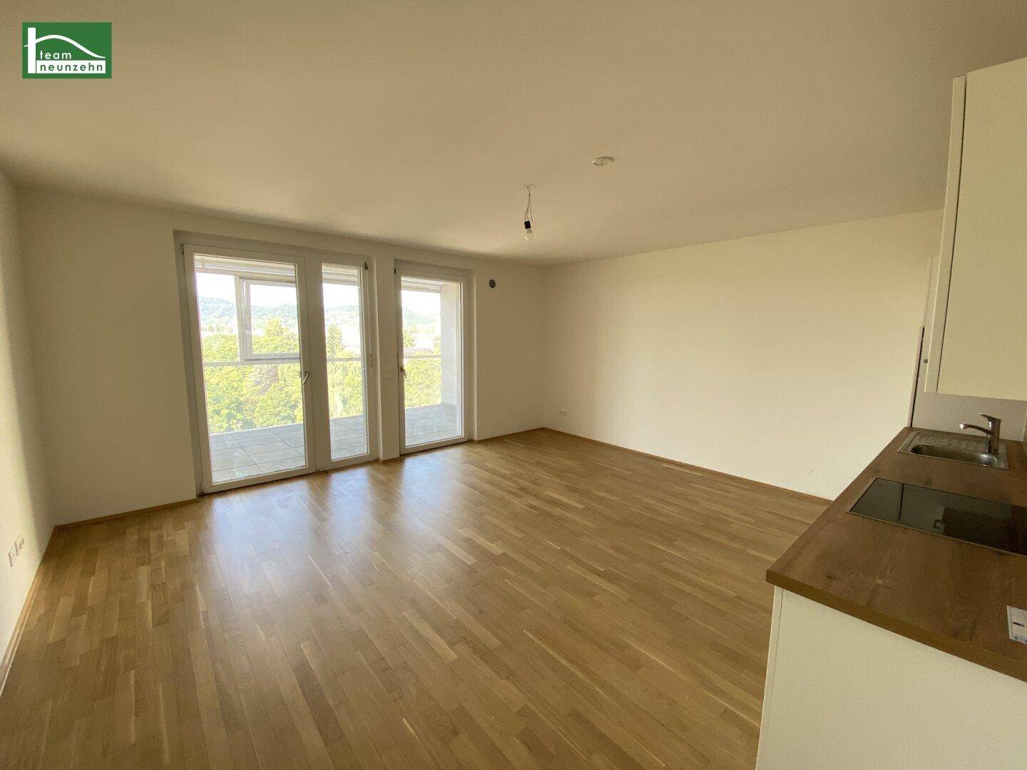 Lichtdurchfluteter Wohnbereich mit großen Fenstern und Blick ins Grüne.