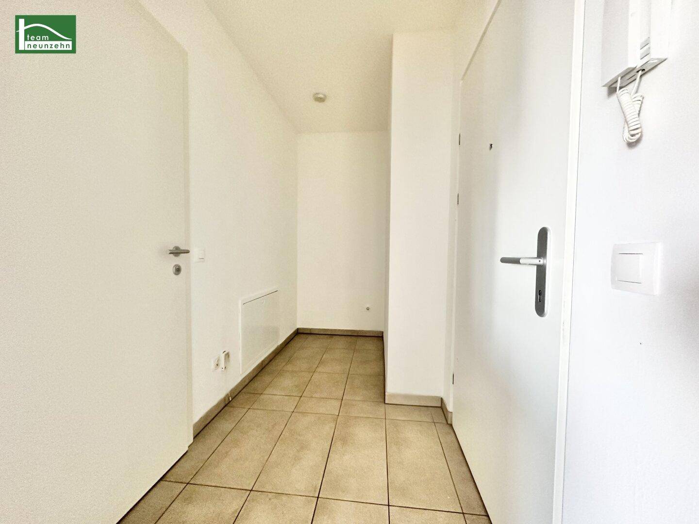 Heller Eingangsbereich mit Fliesenboden und weißen Türen.