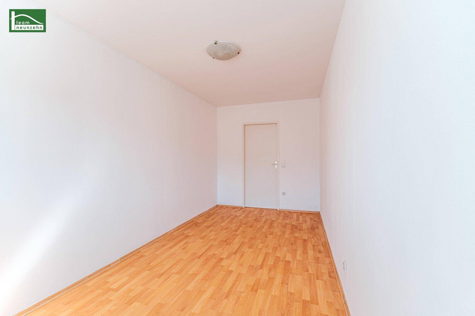 Unmöbliertes Zimmer mit Parkettboden und weißer Tür, vielseitig nutzbar für individuelle Gestaltungsideen.