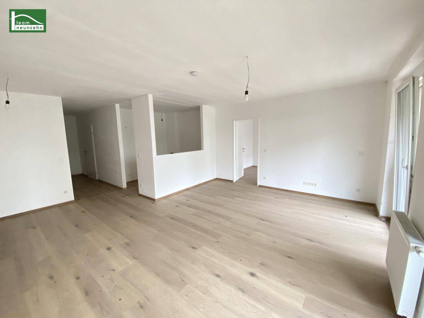 Heller, leerer Wohnbereich mit neuem Holzboden und weißen Wänden, bereit zur individuellen Gestaltung.