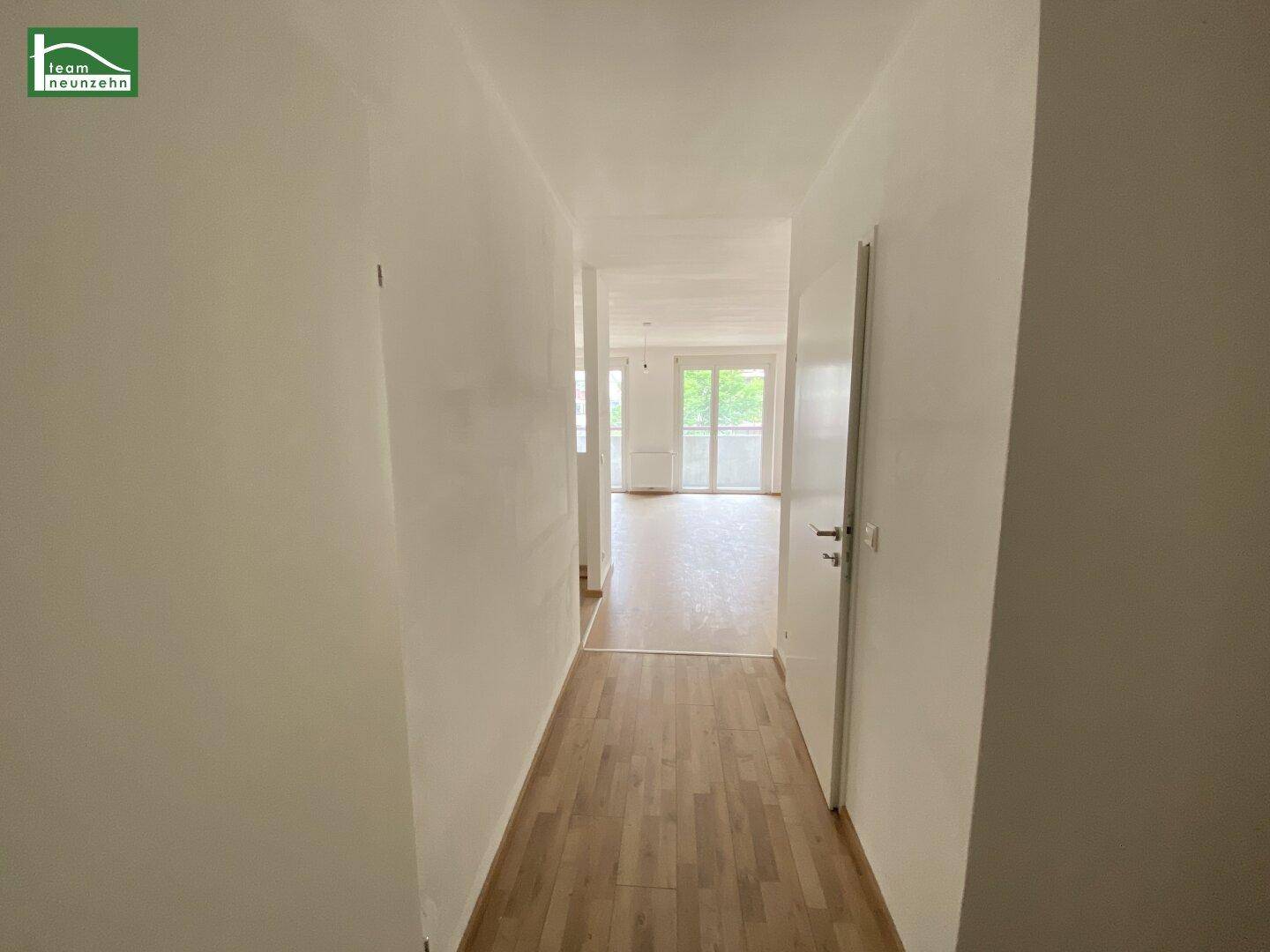 Langer, heller Flur mit Laminatboden, der zu den Wohnbereichen der Wohnung führt.