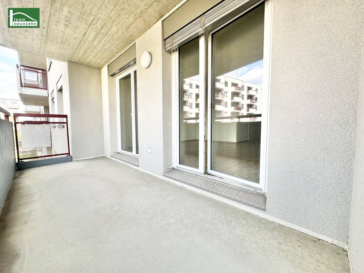Geräumiger Balkon mit Betonboden und Blick auf die umliegenden Gebäude.