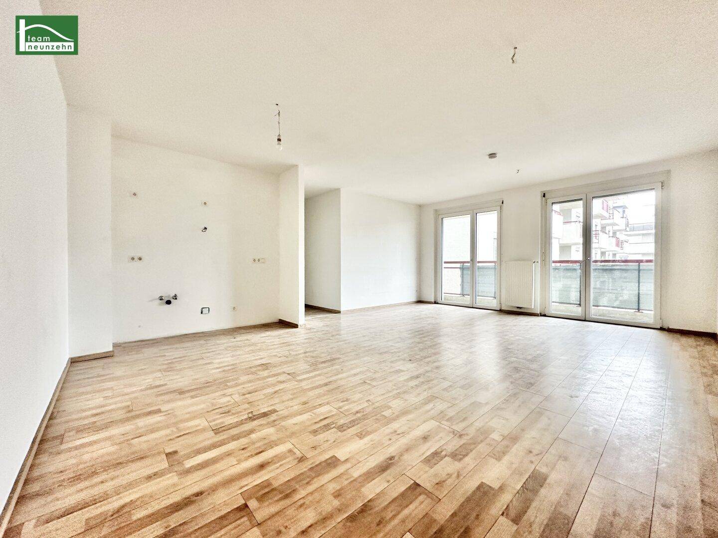 Helles, leeres Zimmer mit Holzboden und Zugang zu einem französischen Balkon, ideal für offenes Wohnen.