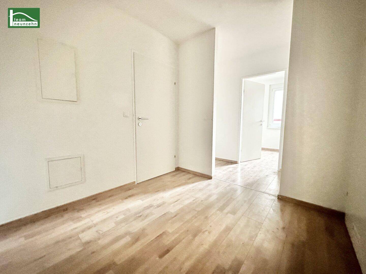 Heller Flur mit Holzboden und weißen Türen, der verschiedene Bereiche der Wohnung verbindet.