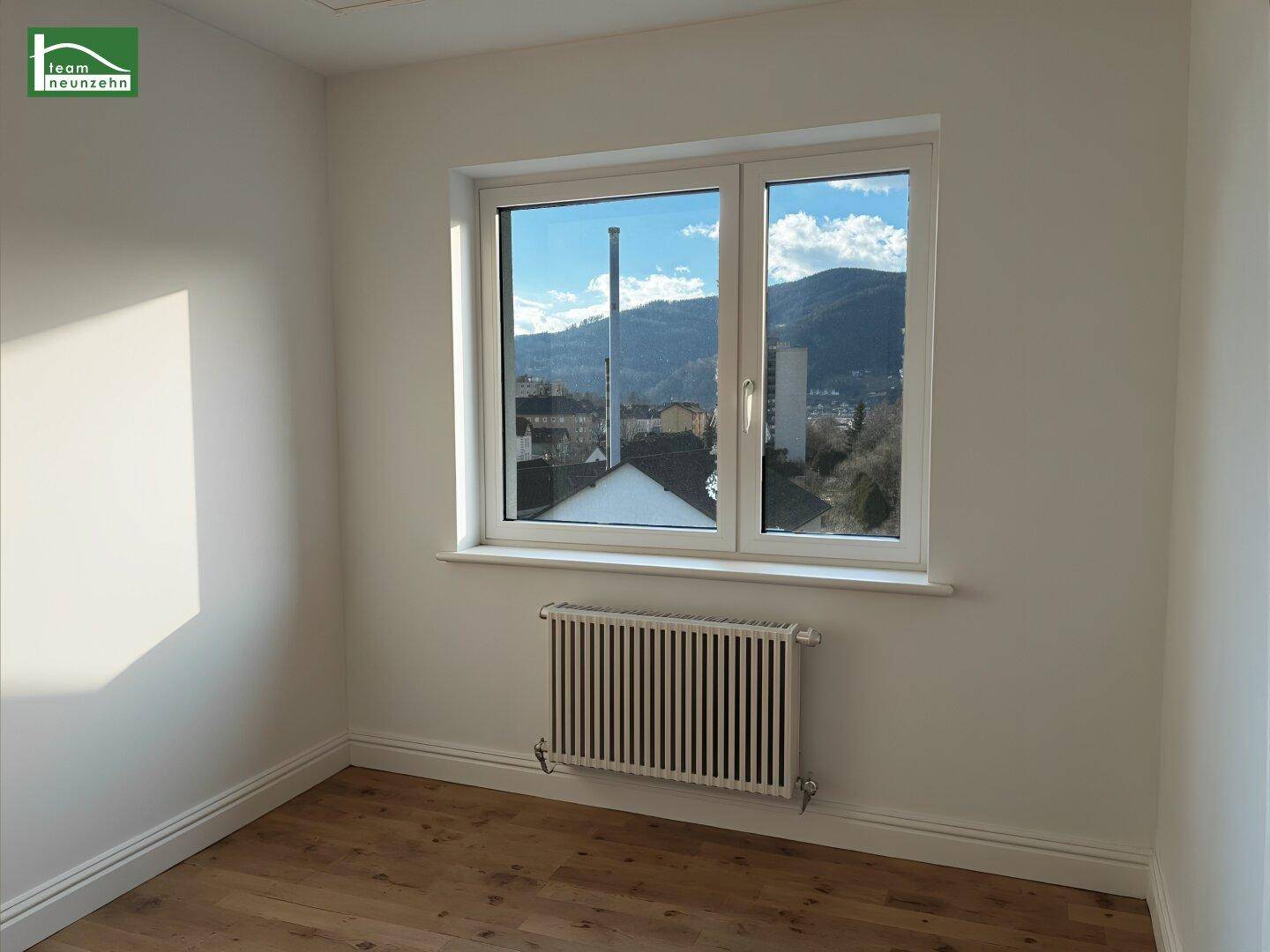 Renoviertes Zimmer mit neuem Holzboden und weitem Blick auf die Berge.