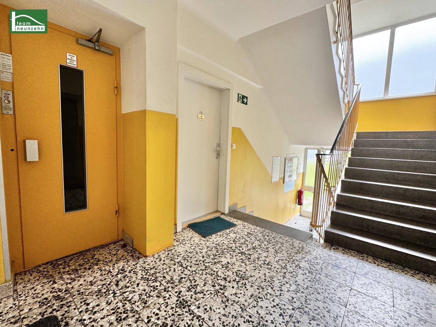 Gemeinschaftlicher Treppenaufgang mit Terrazzoboden und Zugang zum Aufzug.