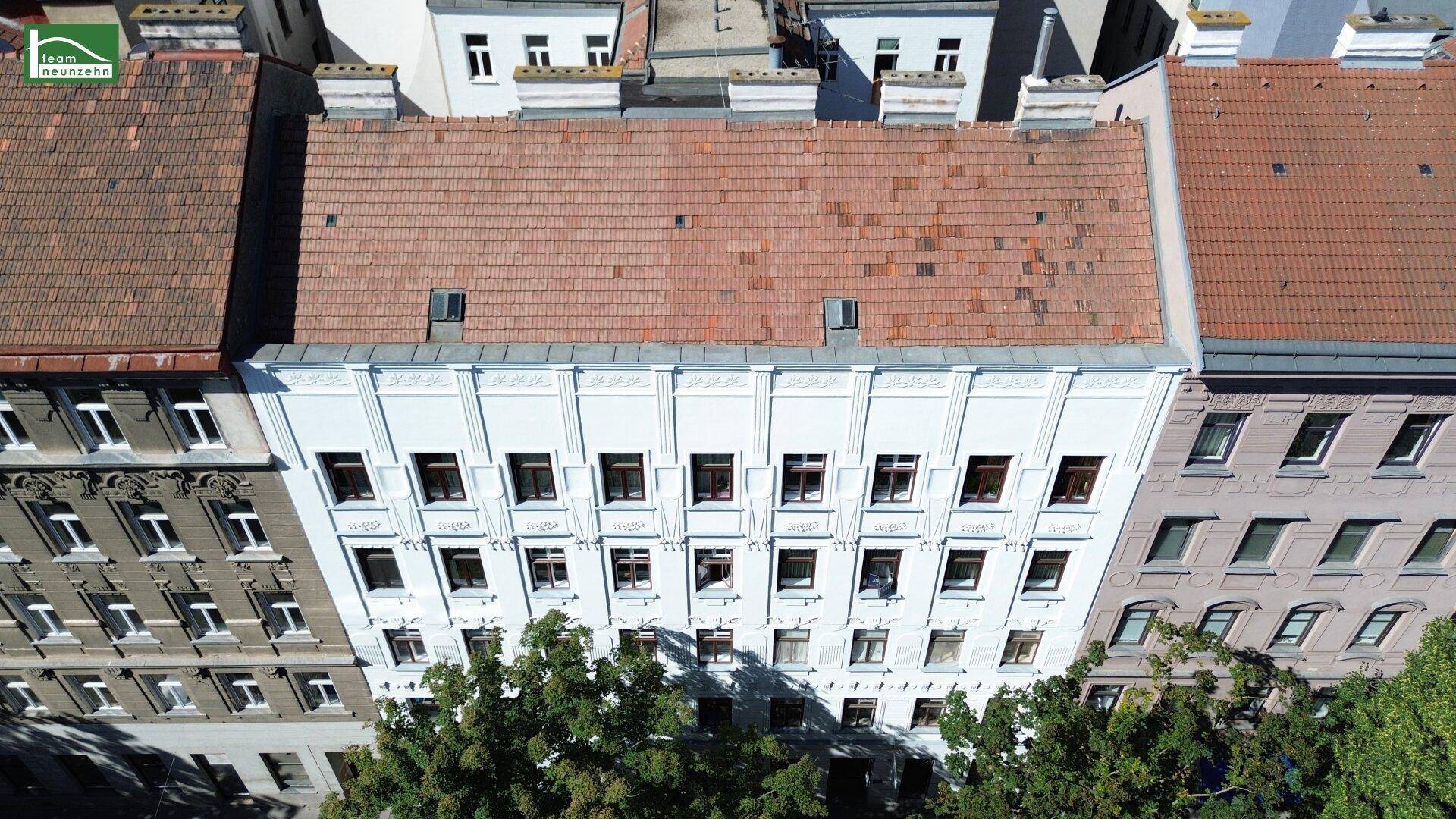 Luftaufnahme des Gebäudes mit rotem Ziegeldach, Dachfenstern und umliegenden Häusern.