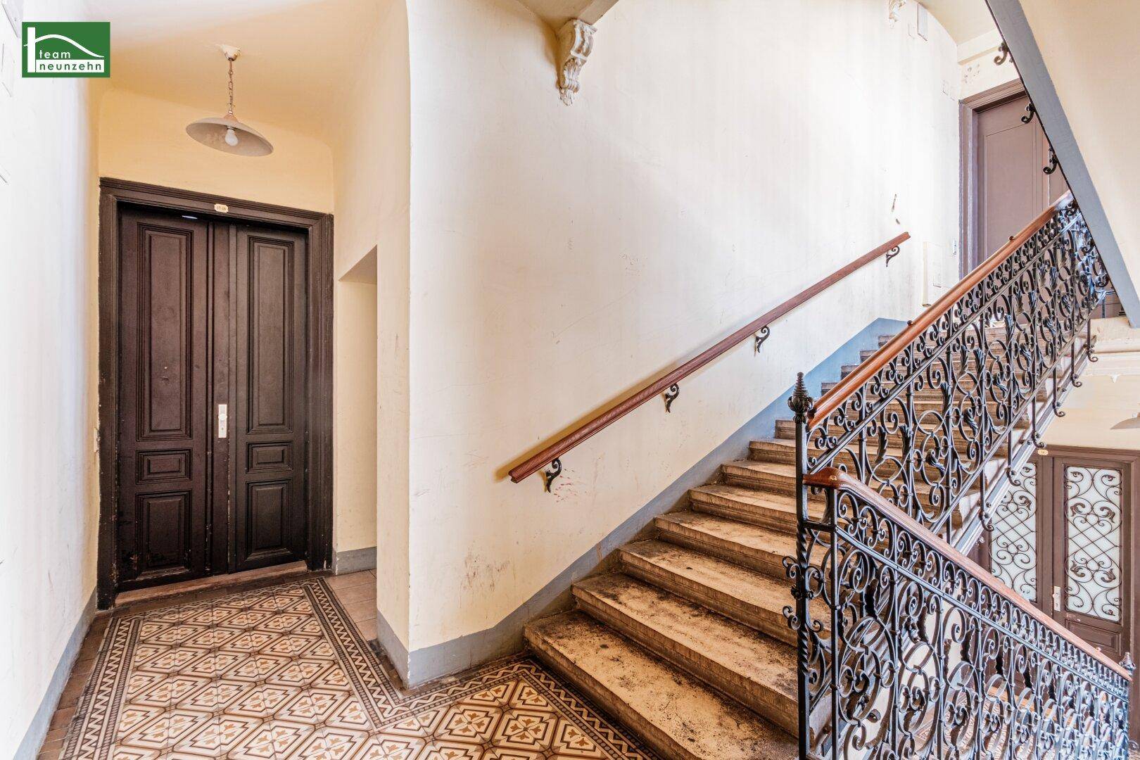 Historisches Treppenhaus mit kunstvollem Geländer und einem alten Aufzug in einem Altbau.