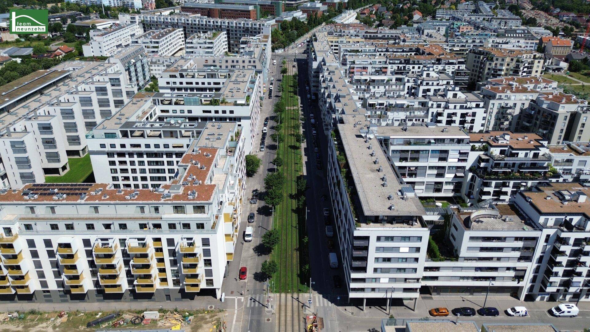 Weitläufige Luftaufnahme der modernen Wohnsiedlung mit viel Grün und städtischer Infrastruktur.
