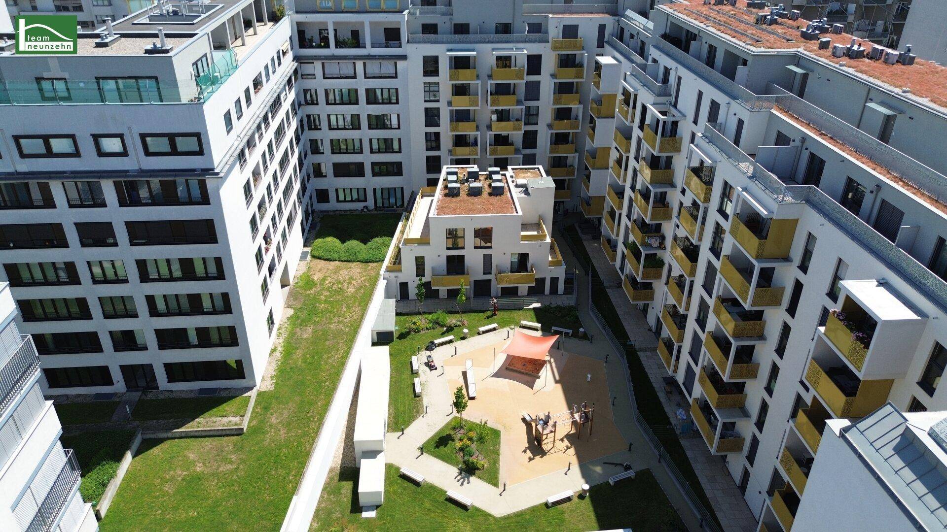 Innenhof der Wohnanlage mit modernem Spielplatz und weitläufigen Grünflächen für Bewohner.