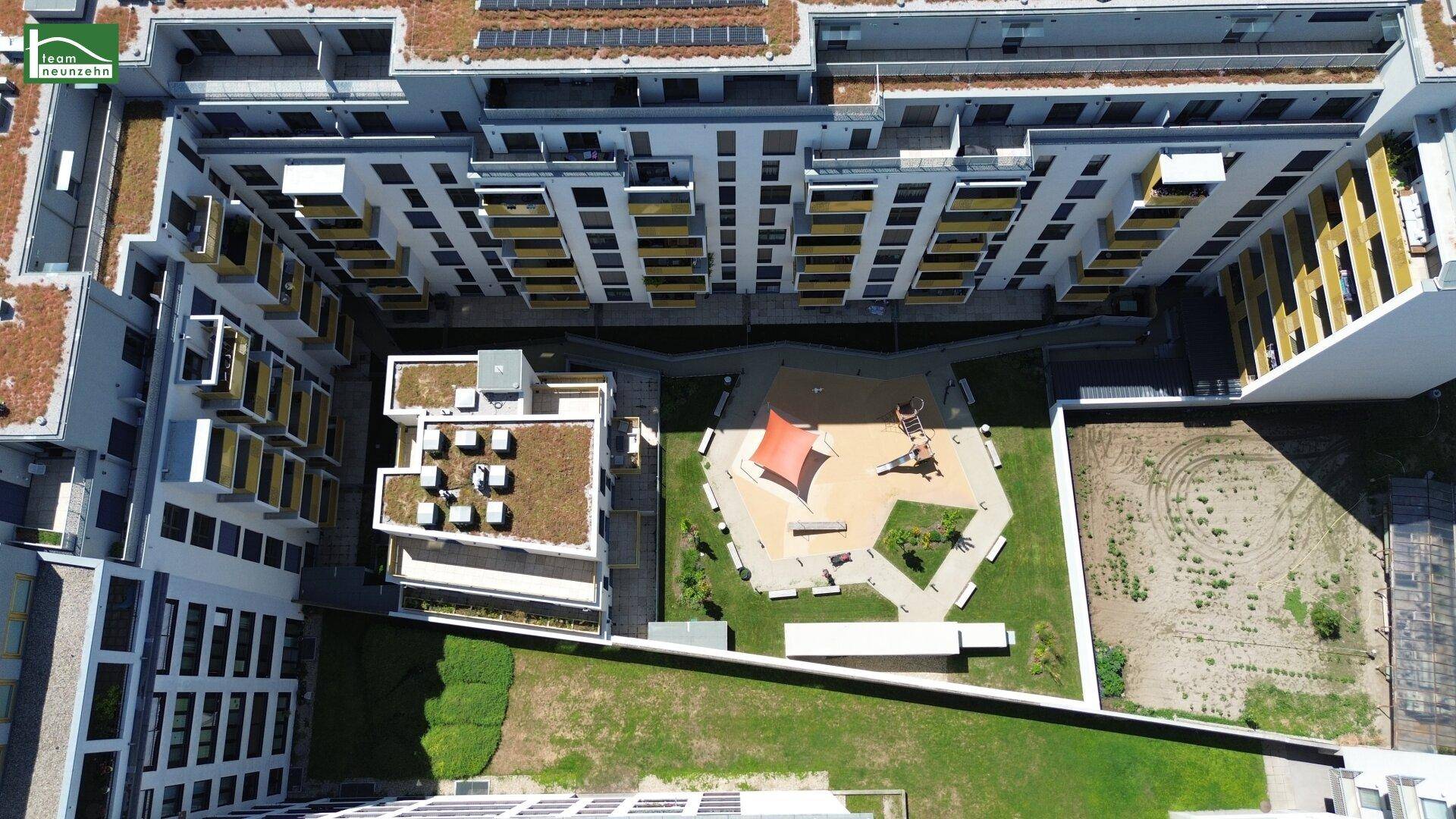 Vogelperspektive auf den Innenhof mit Spielplatz und Grünflächen der modernen Wohnanlage.