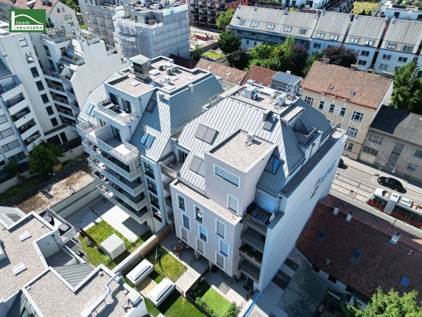 Luftaufnahme des modernen Wohnkomplexes mit begrünten Innenhöfen und städtischer Infrastruktur in der Umgebung.