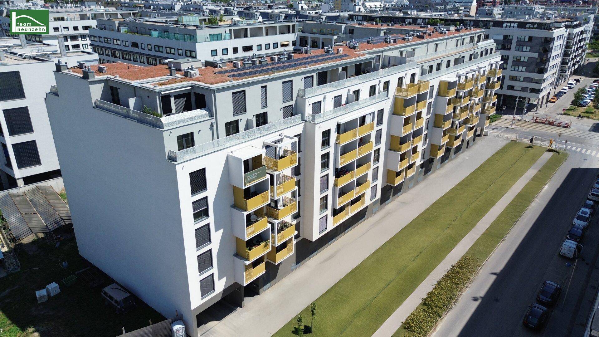 Ansicht der modernen Wohnanlage mit zahlreichen Balkonen und gepflegten Grünflächen entlang der Straße.