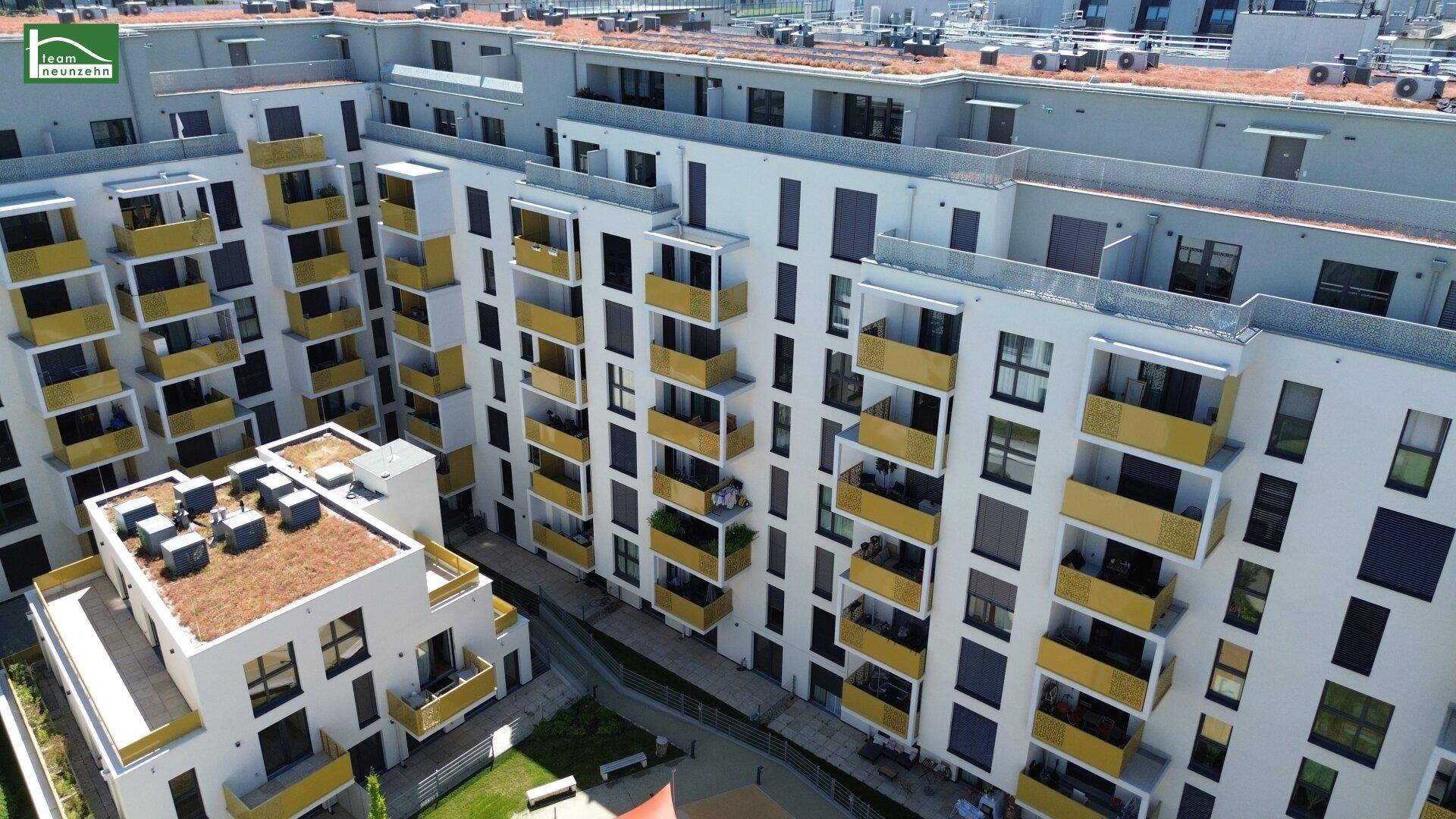 Luftaufnahme eines modernen Wohnkomplexes mit zahlreichen Balkonen und begrünten Dächern.