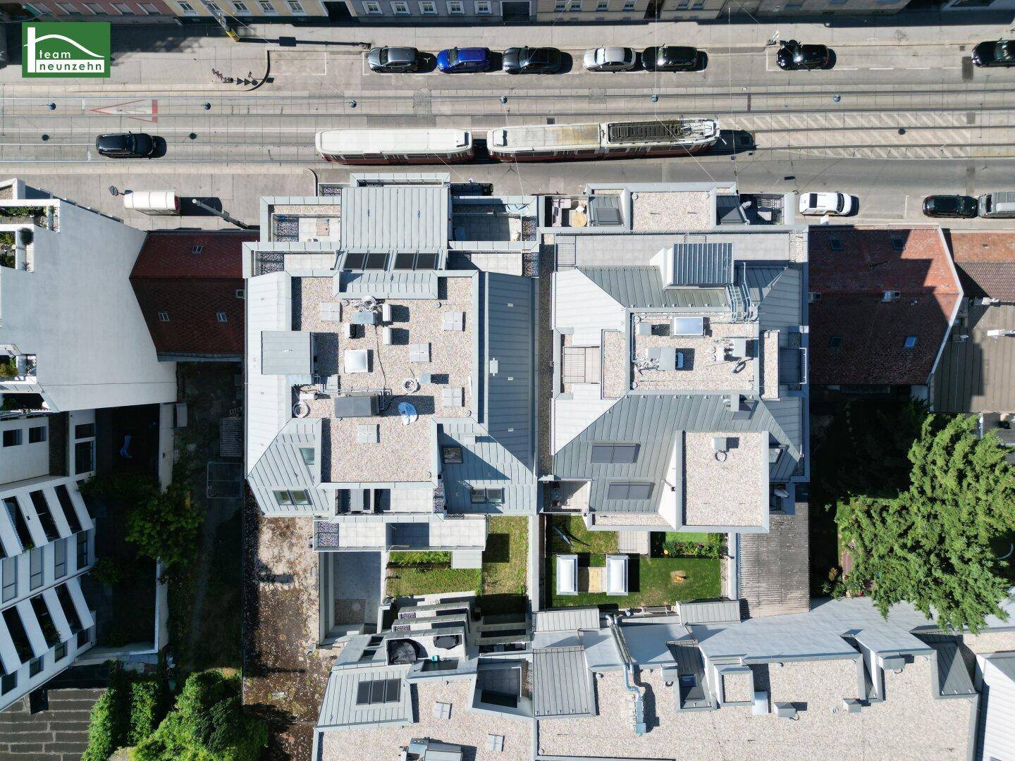 Draufsicht auf den Wohnkomplex mit Dachstrukturen, Innenhöfen und angrenzender Straße.