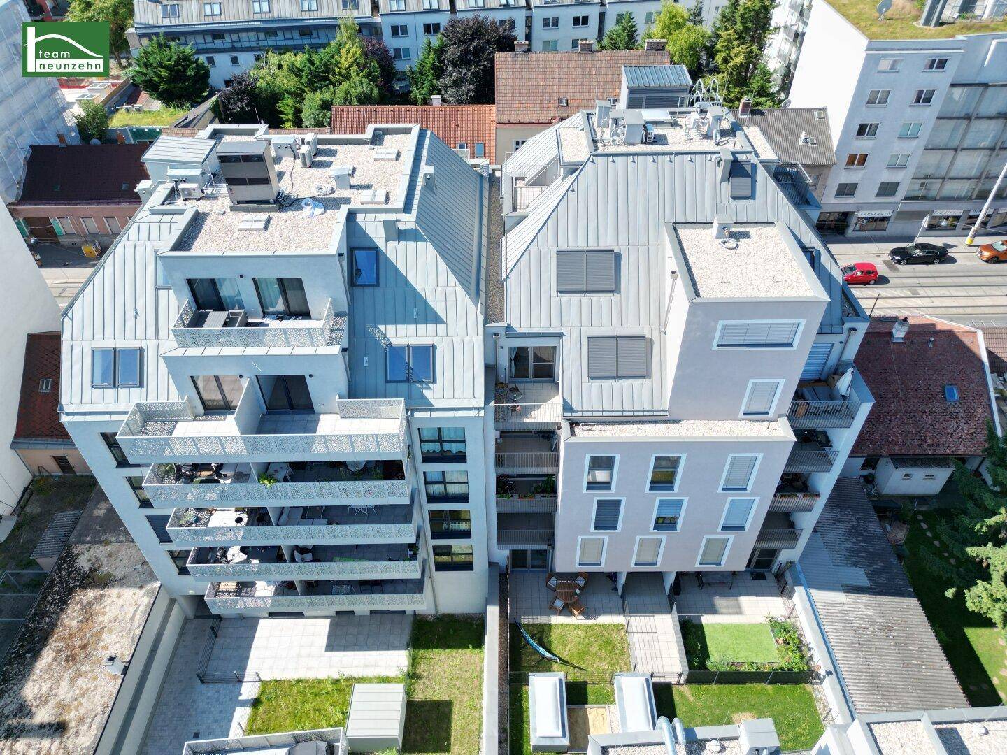 Luftaufnahme eines modernen Wohnkomplexes mit Dachterrassen und begrünten Innenhöfen.