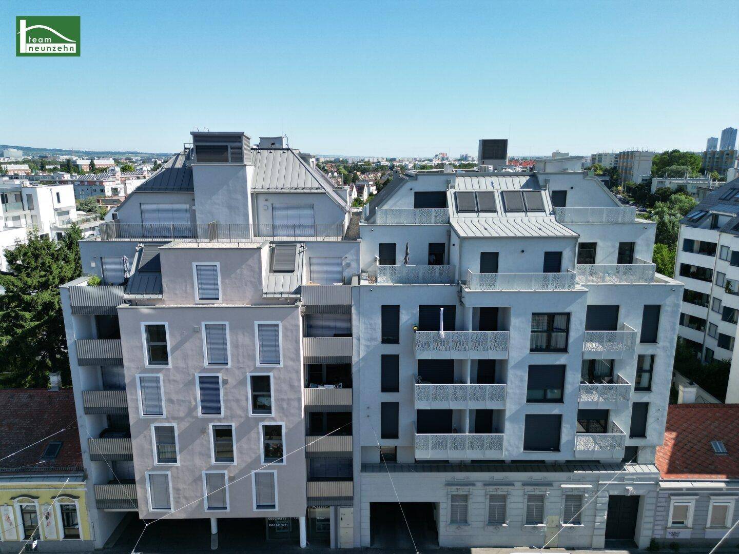 Moderne Wohngebäude mit mehreren Etagen und Balkonen unter klarem blauem Himmel.