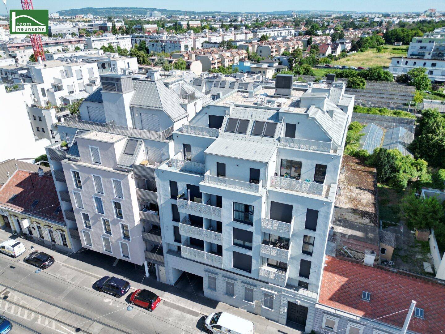 Luftaufnahme eines modernen Wohnkomplexes mit mehreren Etagen und umliegenden Gebäuden.