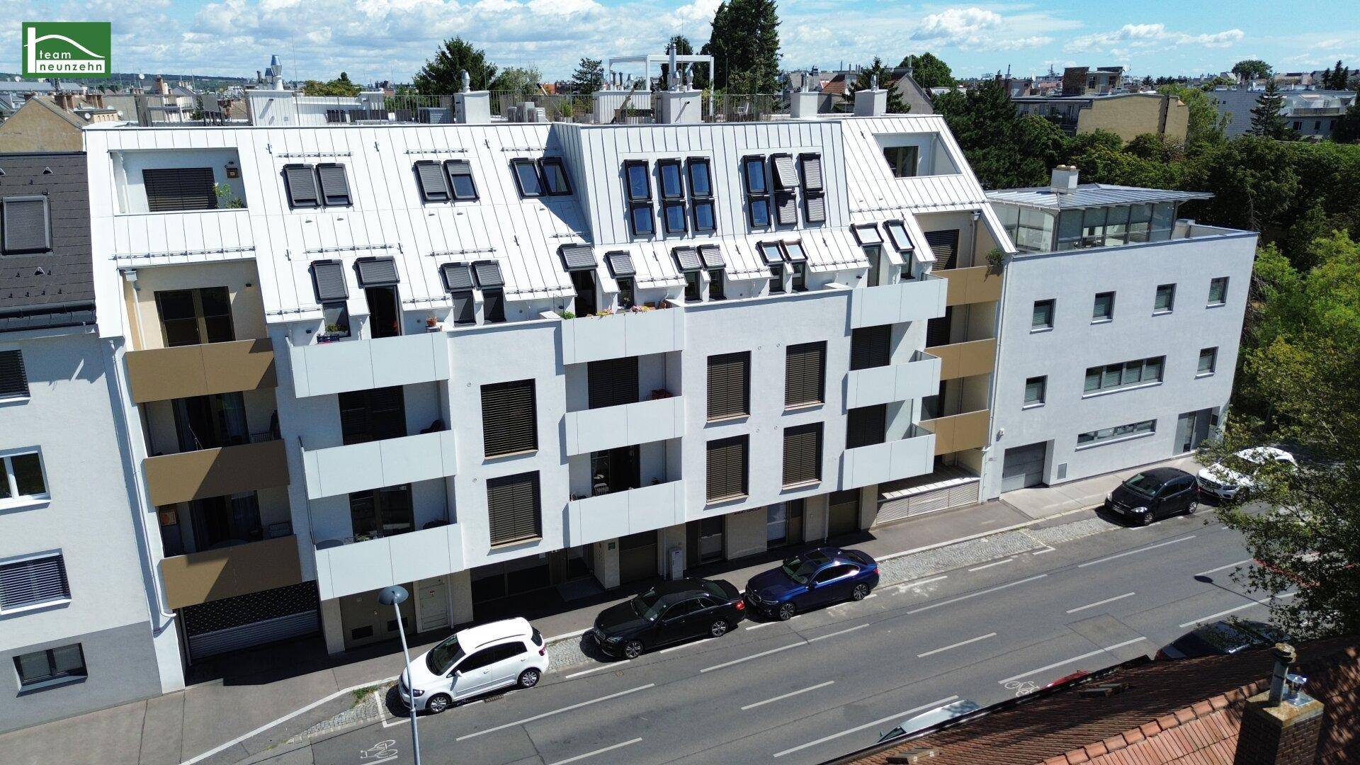 Moderne Wohnanlage mit mehreren Etagen, Balkonen und Dachfenstern an einer Straße.