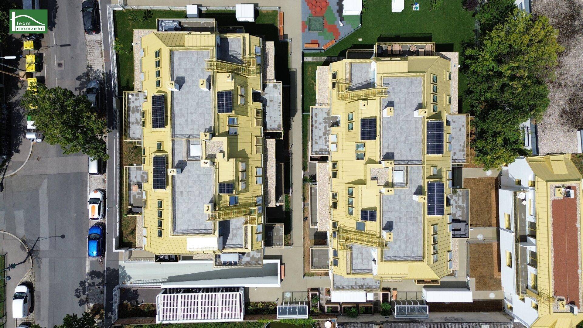 Vogelperspektive der beiden modernen Wohngebäude mit goldenen Dächern und Solaranlagen.