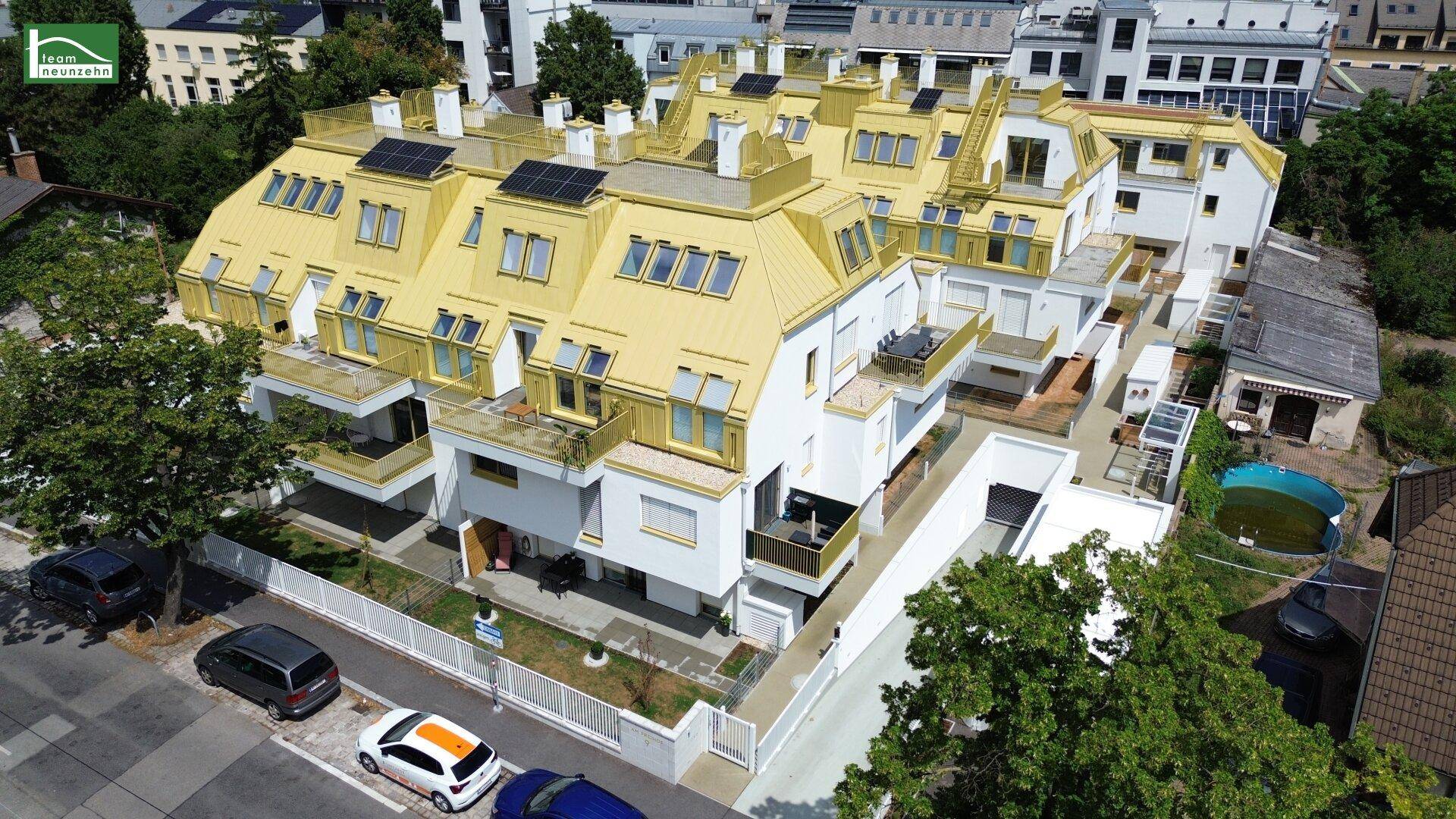 Luftaufnahme des modernen Wohnkomplexes mit gelben Dächern, Balkonen und umliegender städtischer Bebauung.