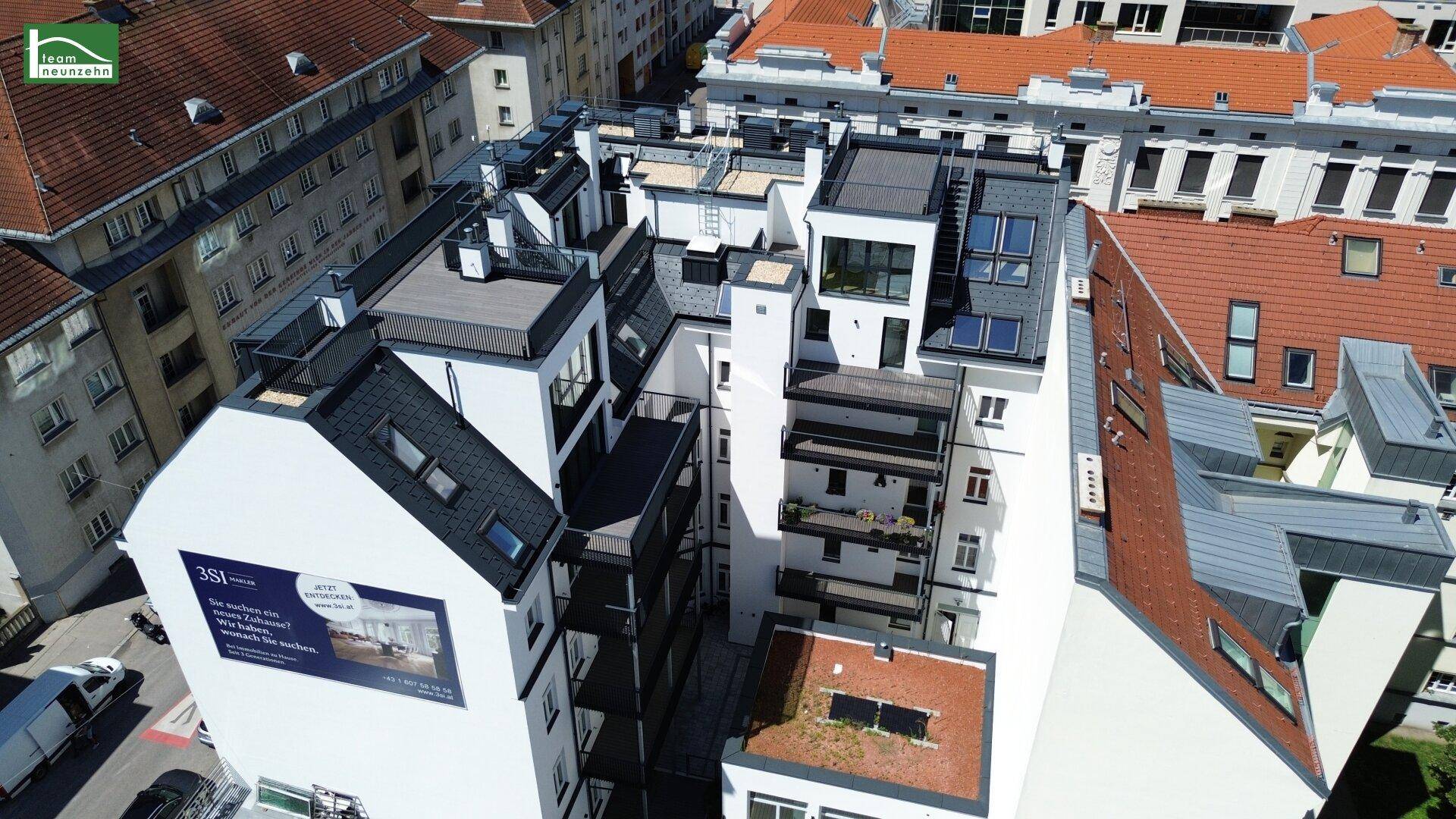 Luftaufnahme des Innenhofs und der Rückseite des Gebäudes mit Balkonen und Dachterrassen.