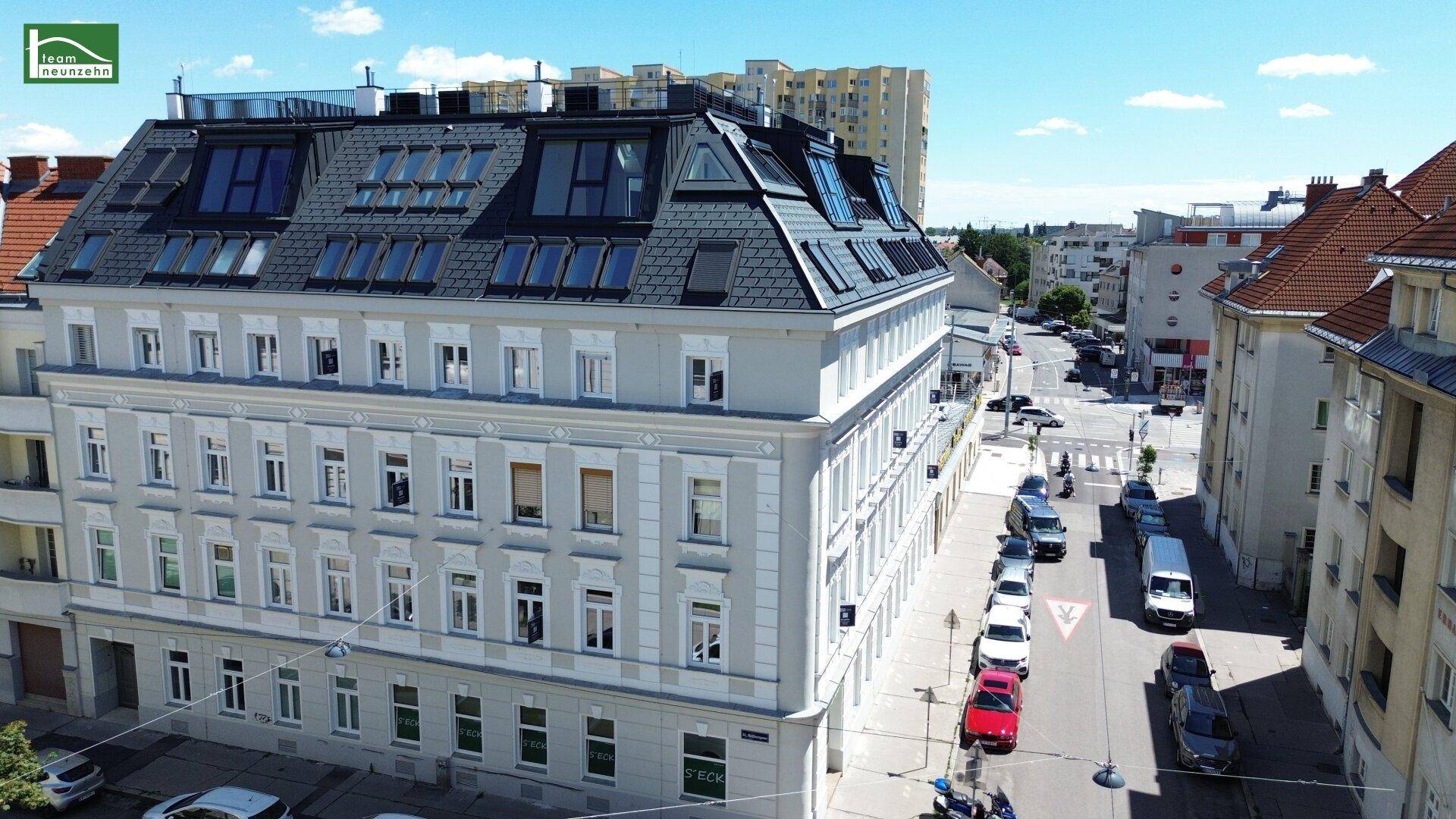 Historisches Gebäude mit modern ausgebautem Dachgeschoss und vielen Dachfenstern an einer Stadtstraße.