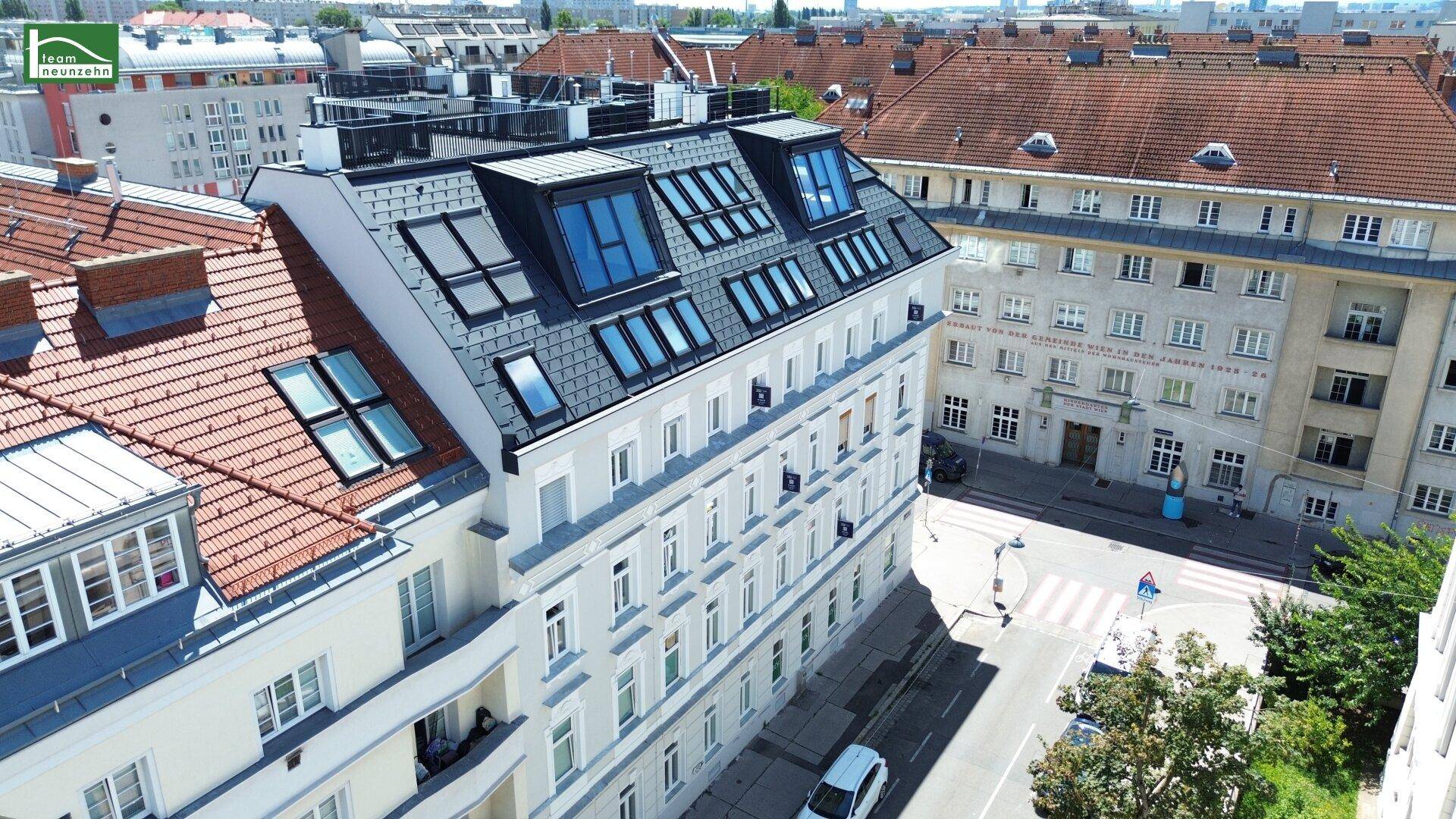 Vogelperspektive eines sanierten Altbaus mit neuem Dachgeschoss und angrenzenden Gebäuden.
