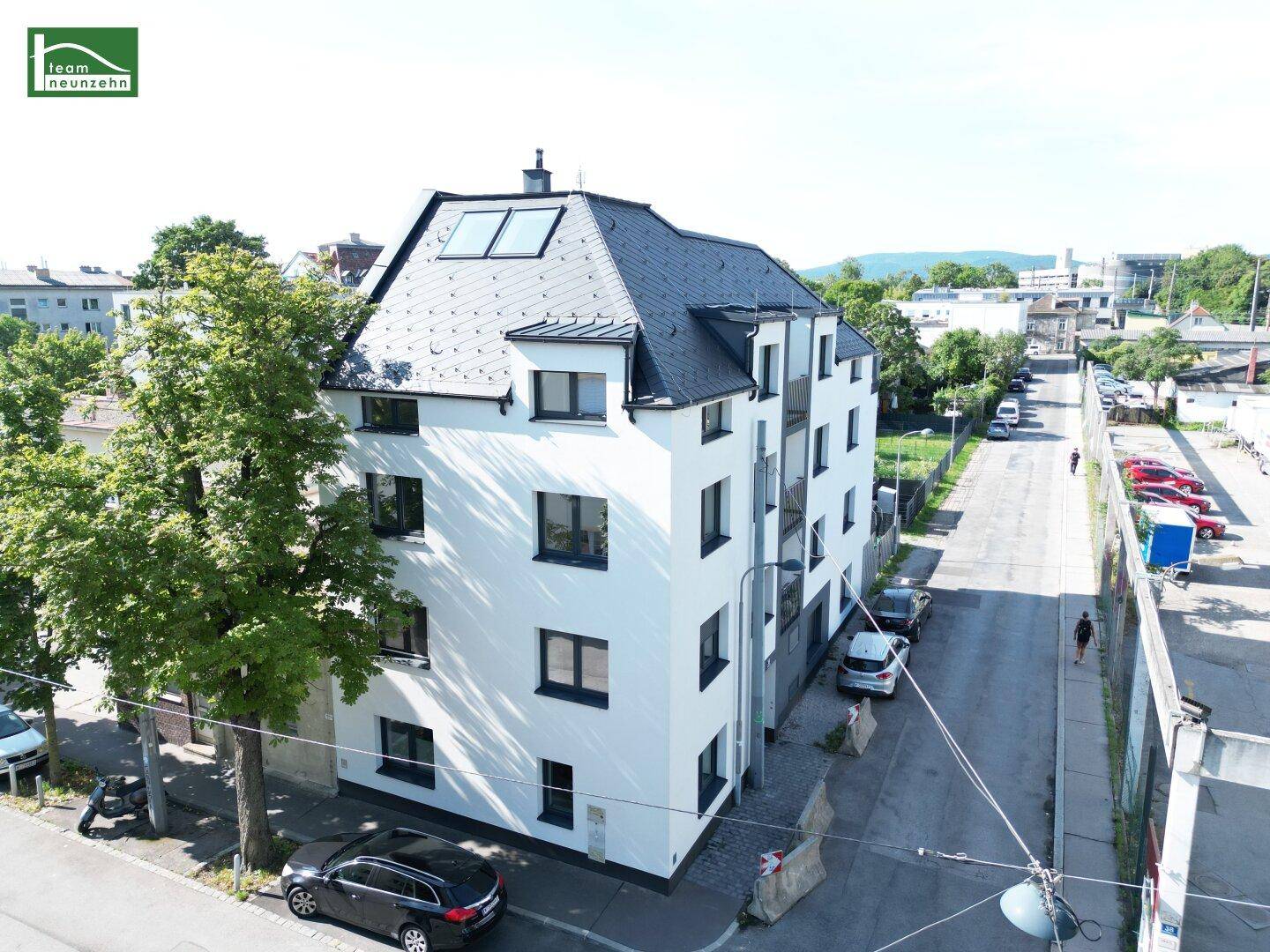 Luftaufnahme des Wohngebäudes mit umliegender Straße und Bäumen, zeigt die städtische Lage.