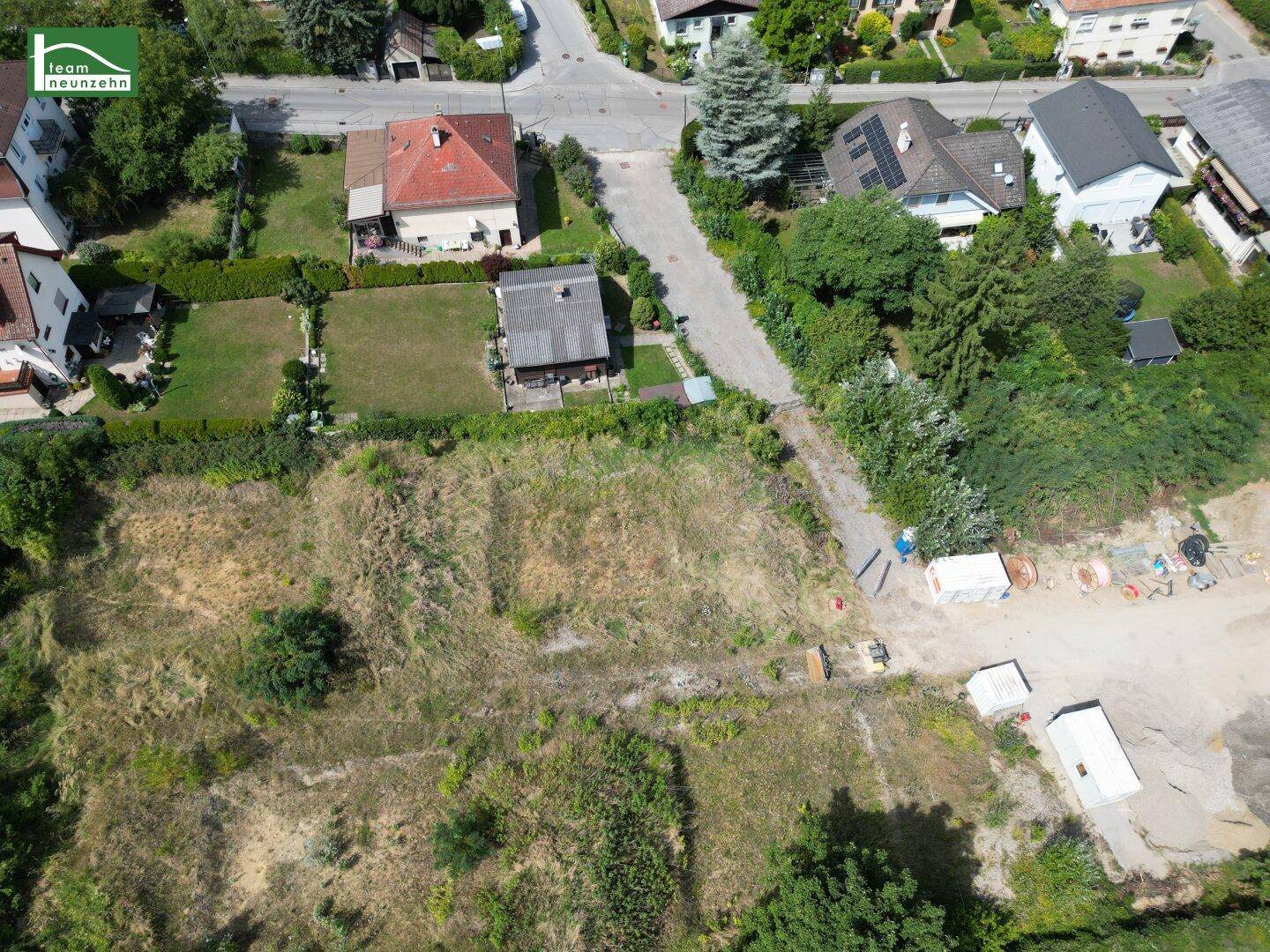 Luftaufnahme eines großen, unbebauten Baugrundstücks mit umliegenden Häusern und Straßen in der Nachbarschaft.