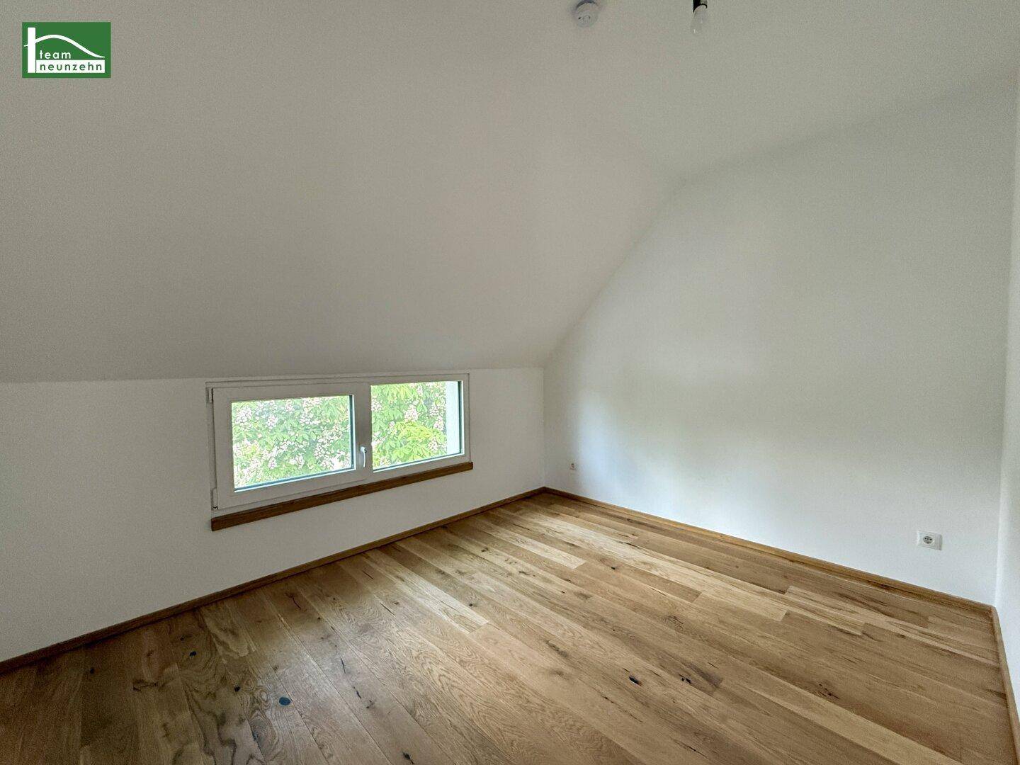 Helles Dachzimmer mit Holzboden und schrägen Wänden, ideal für individuelle Gestaltung.