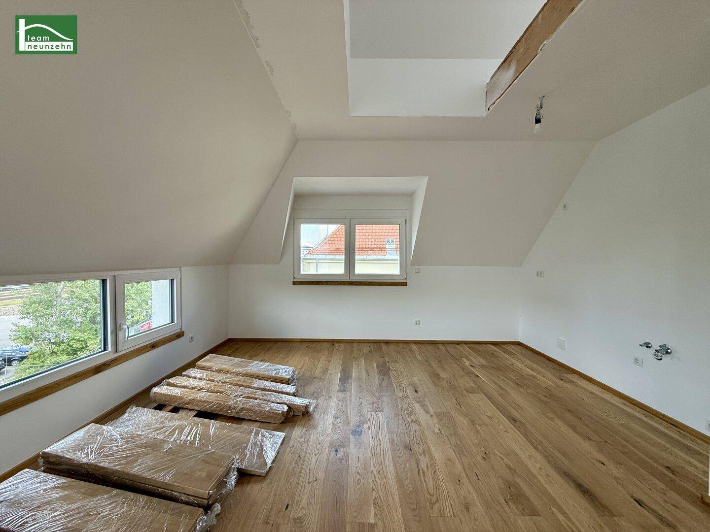 Dachgeschosszimmer mit Holzboden und mehreren Fenstern, bietet Ausblick und viel Helligkeit.