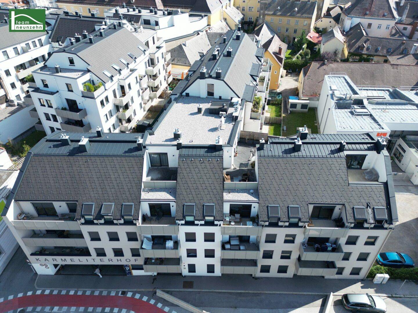 Gesamtansicht der modernen Wohnanlage Karmeliterhof mit zahlreichen Balkonen und Dachterrassen.