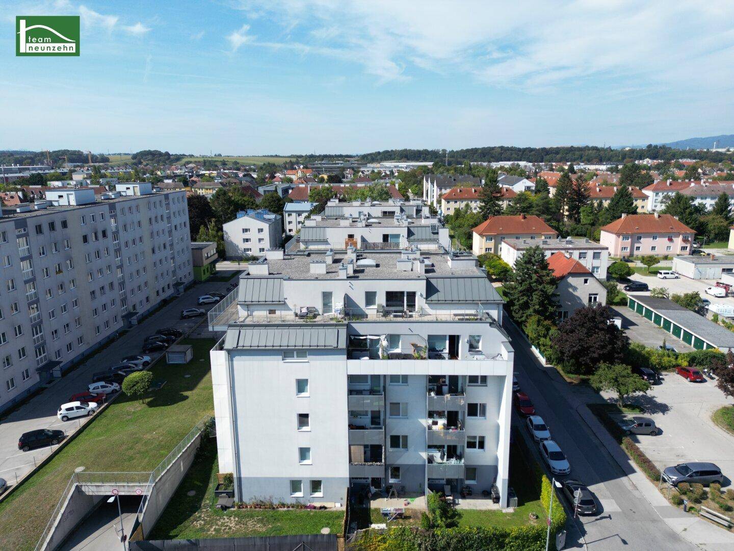Überblick über einen modernen Wohnkomplex in einer städtischen Umgebung mit viel Grün und weiteren Gebäuden.