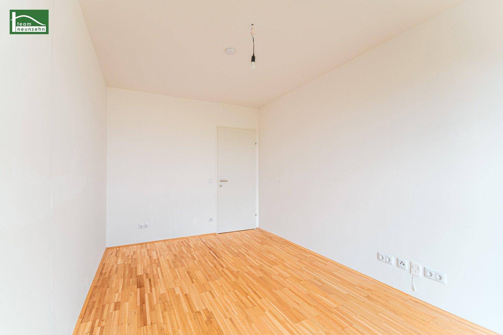 Leeres Schlafzimmer mit Holzboden und weiß gestrichenen Wänden, bereit zur Einrichtung.
