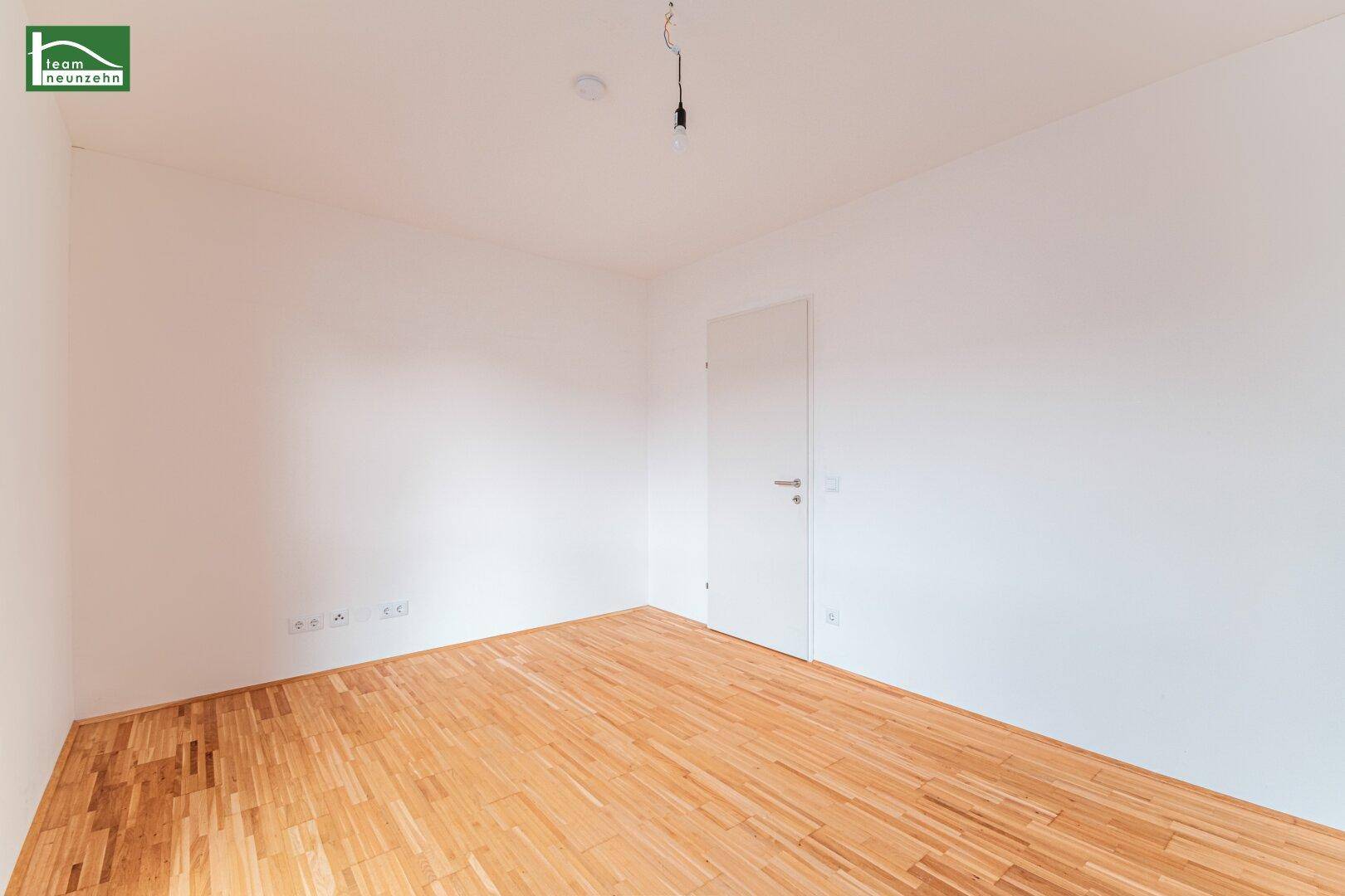 Leeres Zimmer mit Holzboden und weiß gestrichenen Wänden, vielseitig nutzbar.