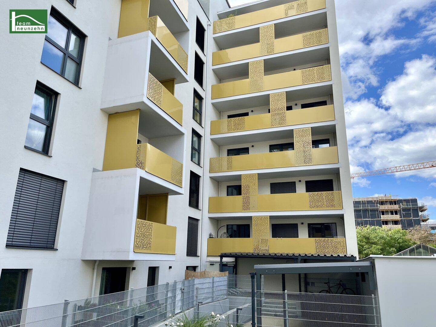 Detailansicht der modernen Fassade mit gelben Balkonen und großen Fenstern.